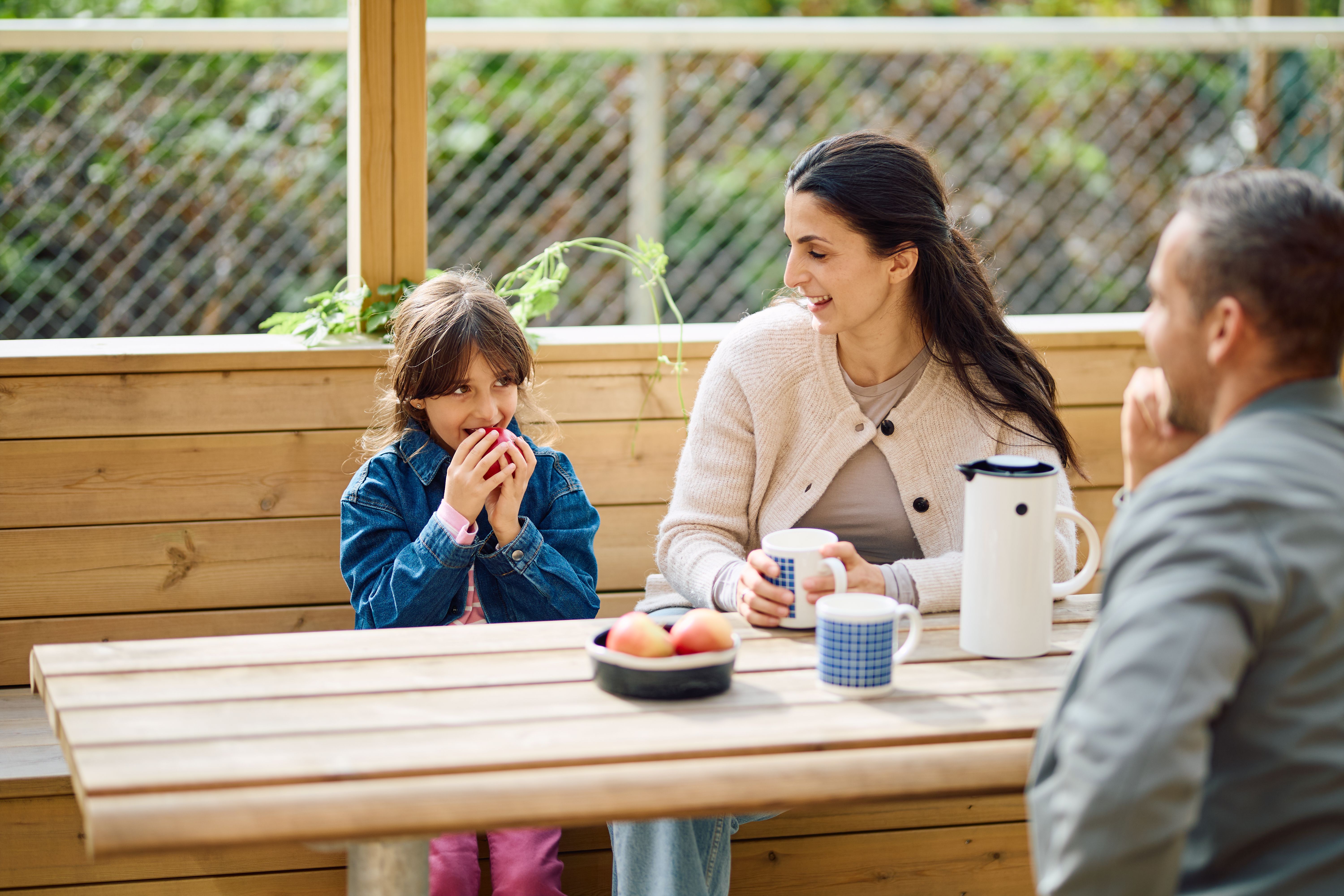 Foto av familie som koser seg ved benkebord