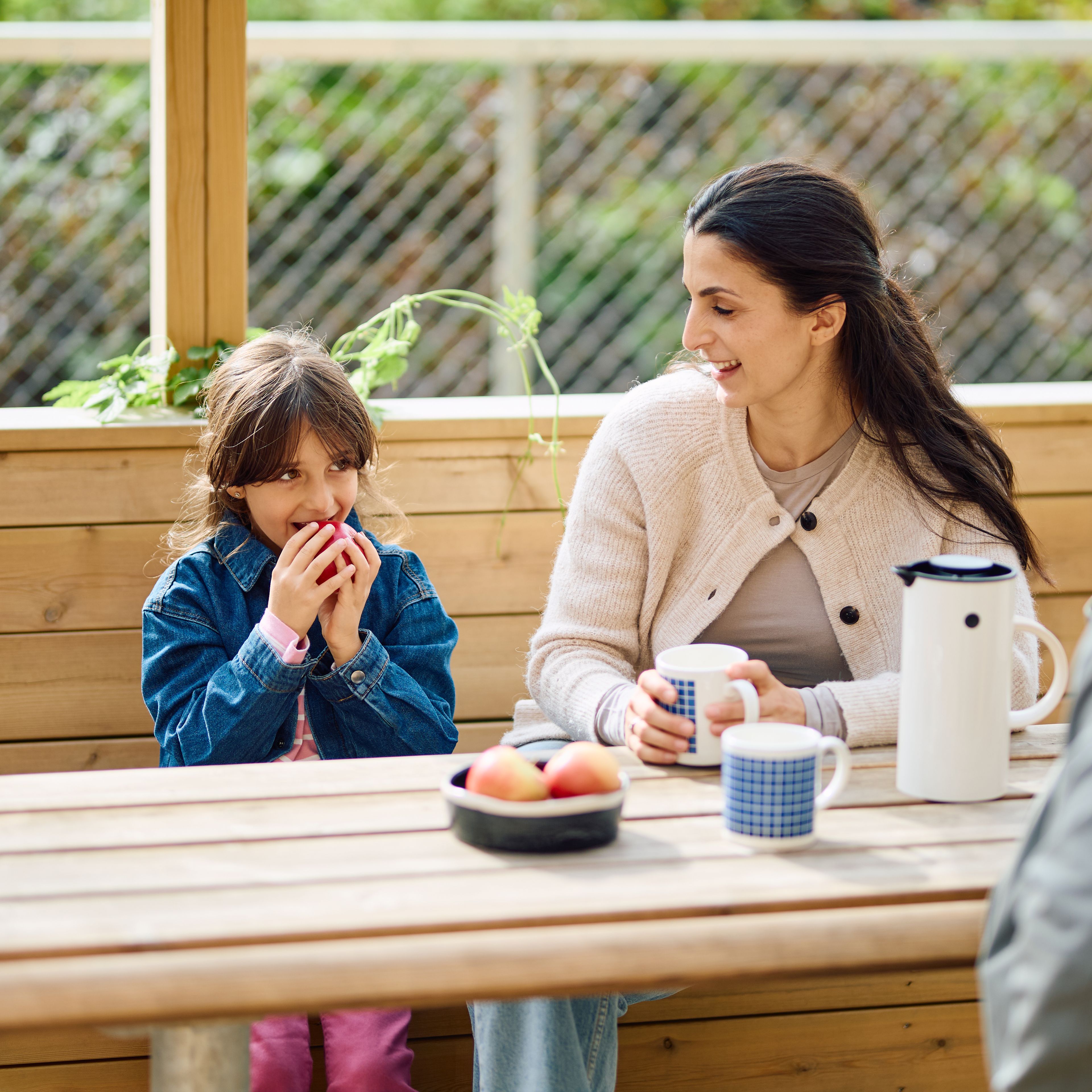 Foto av familie som koser seg ved benkebord