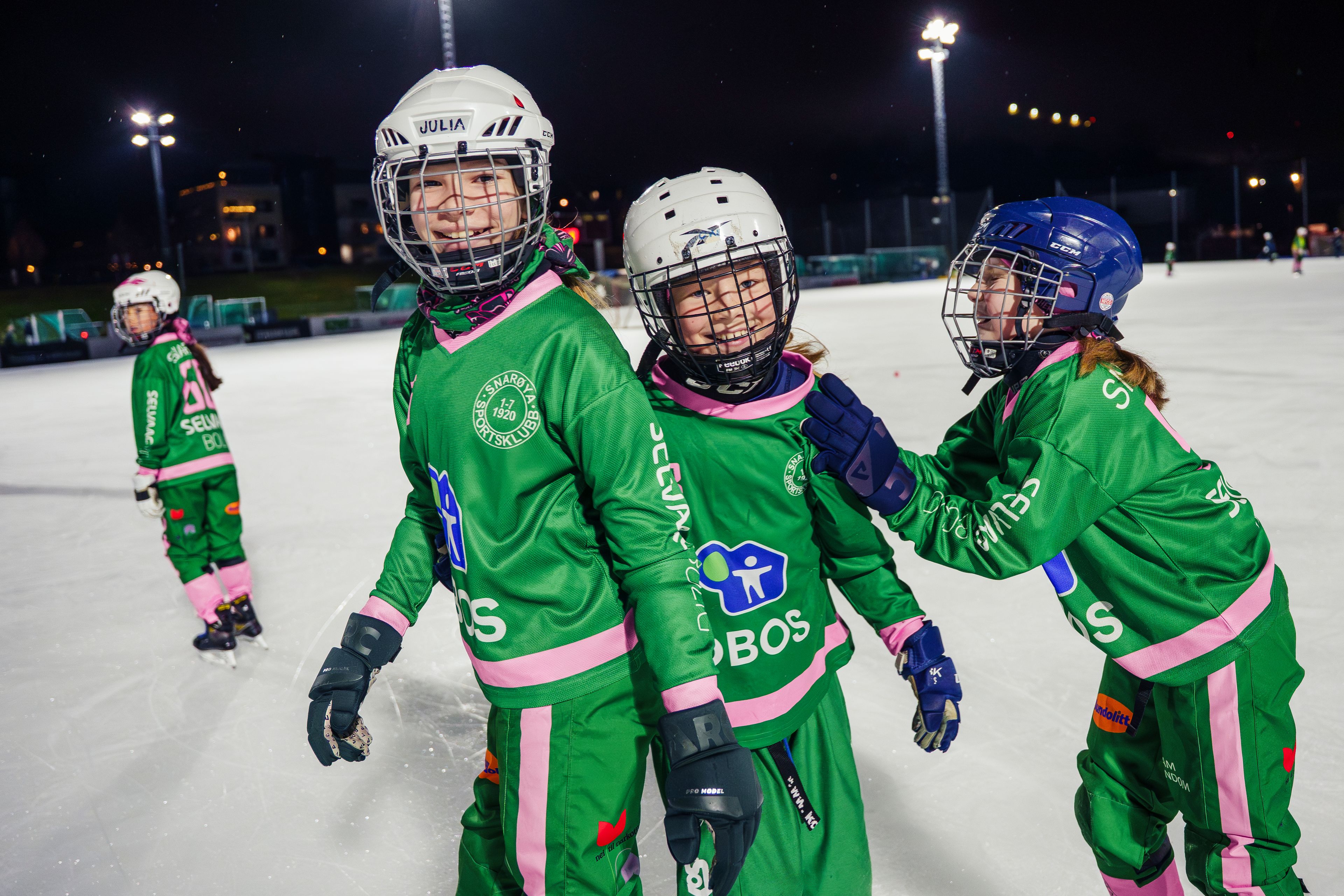 Bilde av tre bandyjenter på isen.