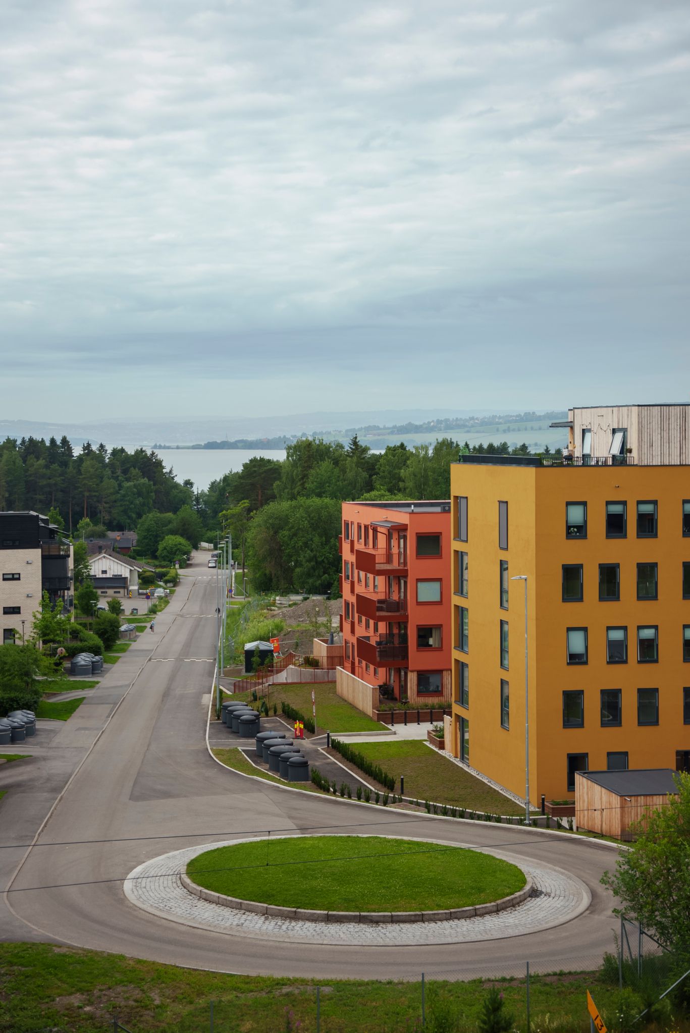Bilde av gule og røde leilighetsbygg, med bilvei og rundkjøring i front