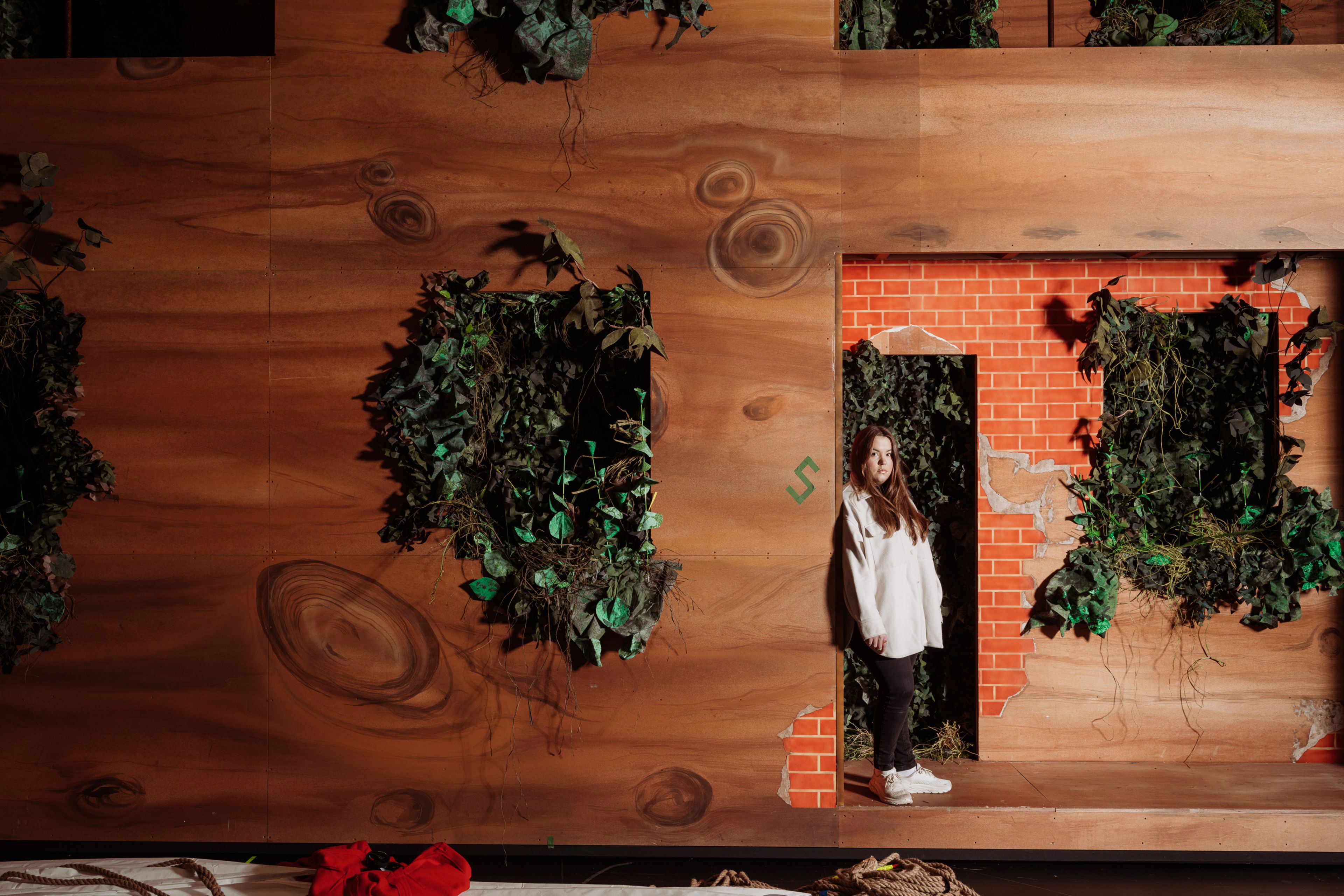 Ina Svenningdal lenar seg mot ein vegg i Into the woods-kulissane.