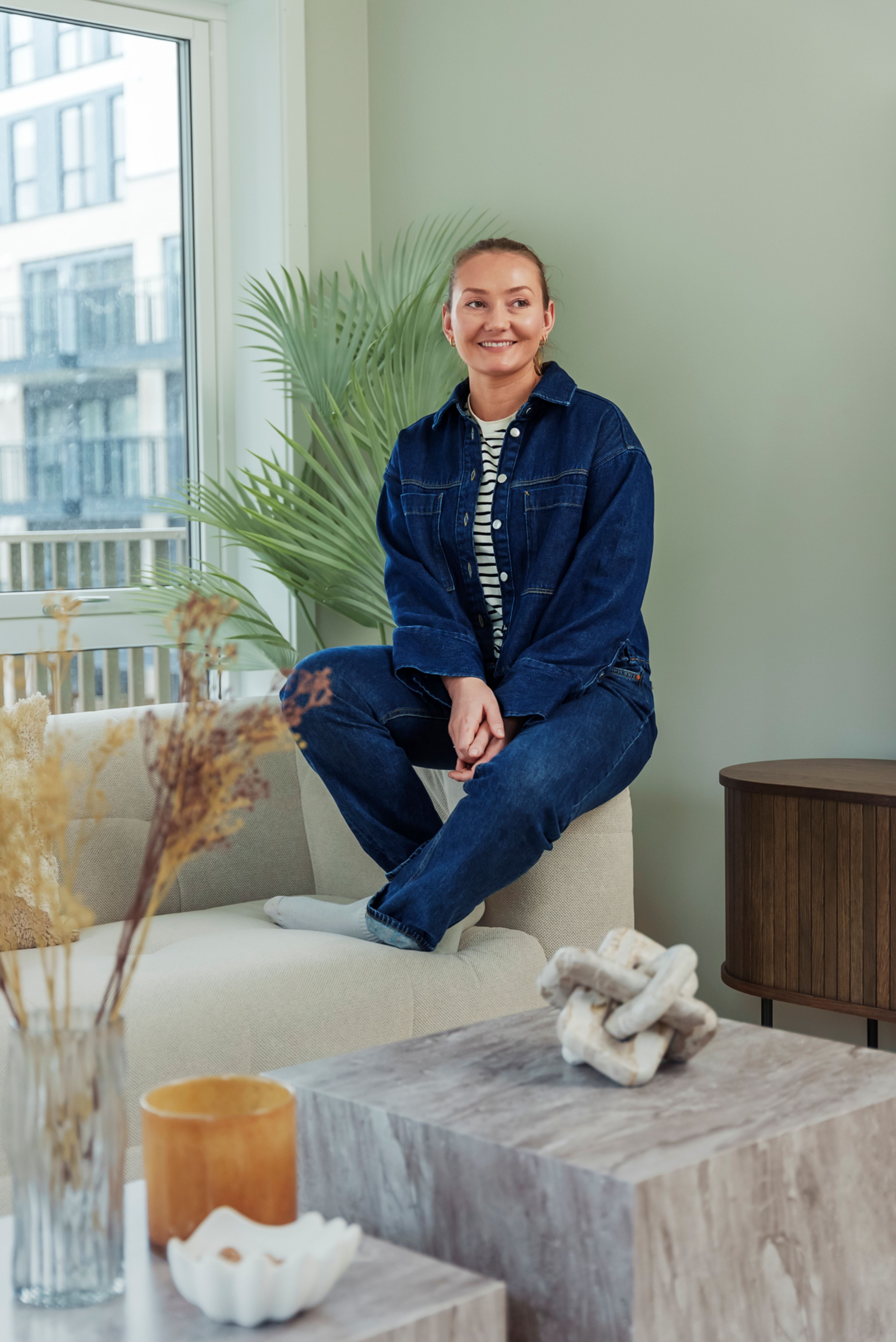 Stylist fra Bohus sitter på en hvit sofa i en leilighet i MIDT.