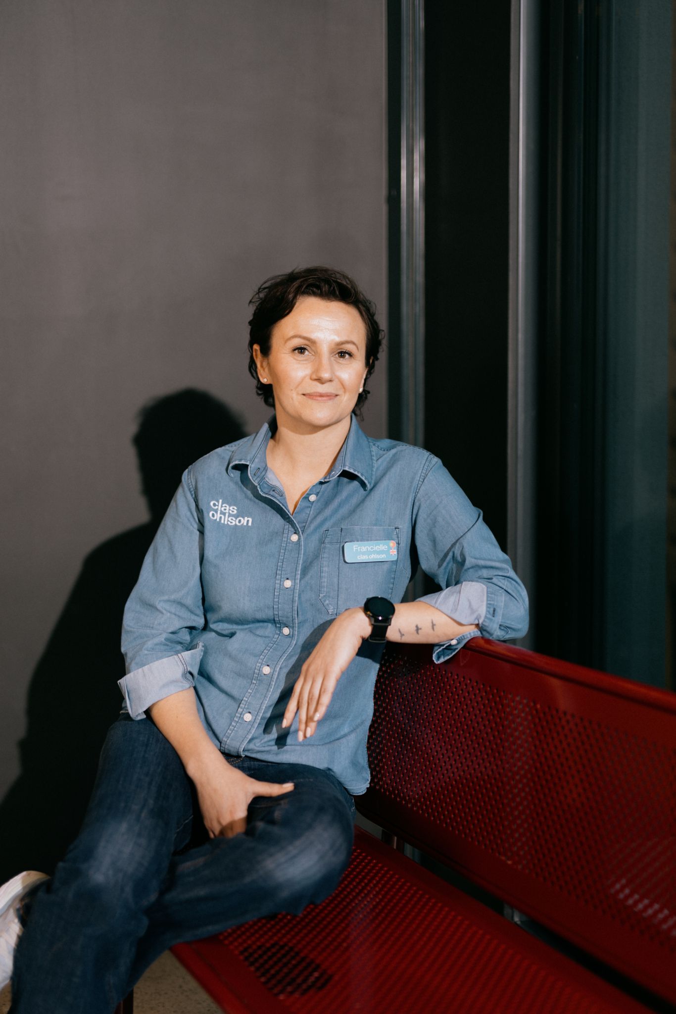 Foto av Francielle Lubke som sitter på en rød benk og smiler et lite smil mot kamera.