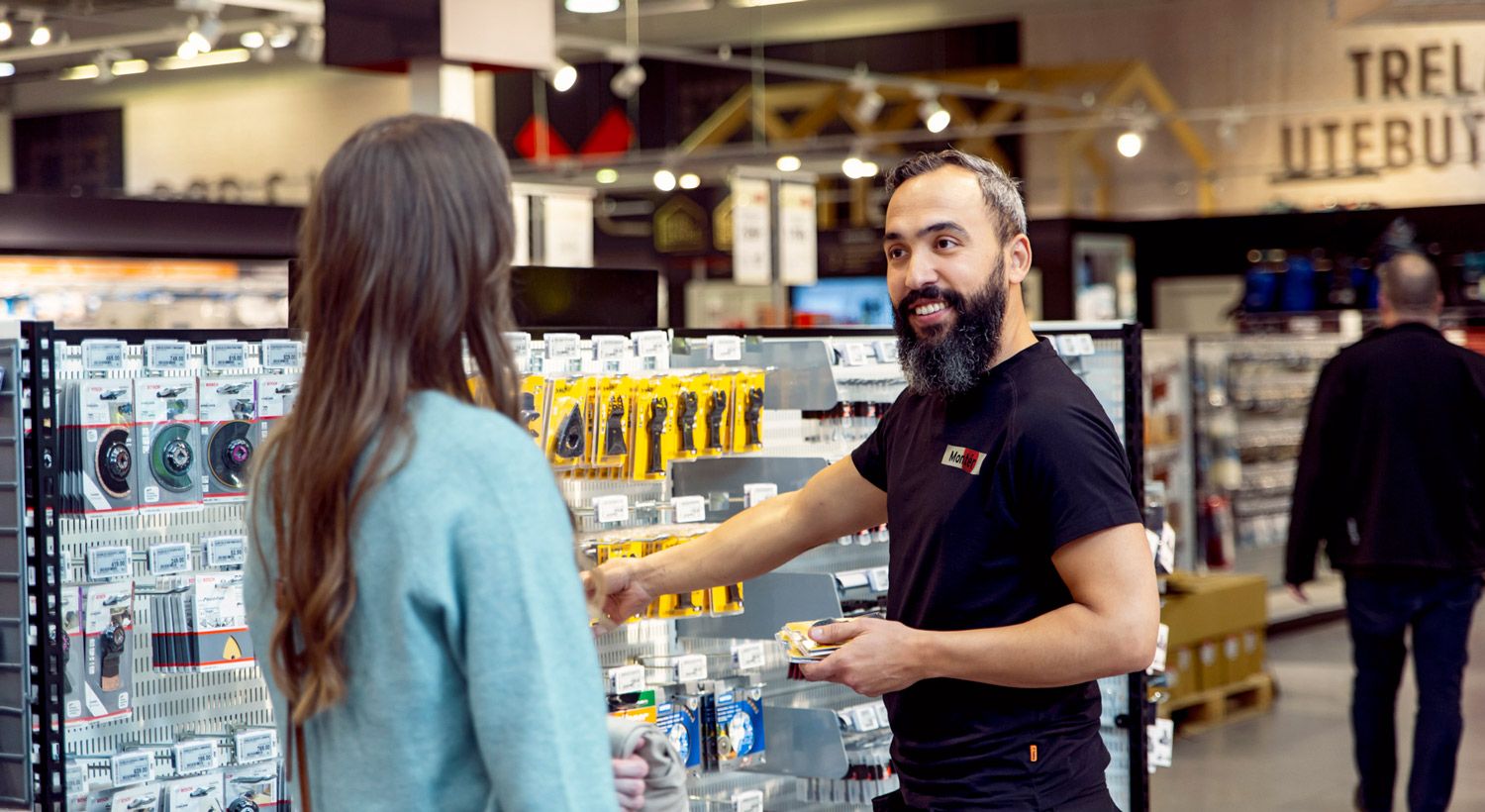 En mannlig ansatt i monter hjelper en kunde i butikken