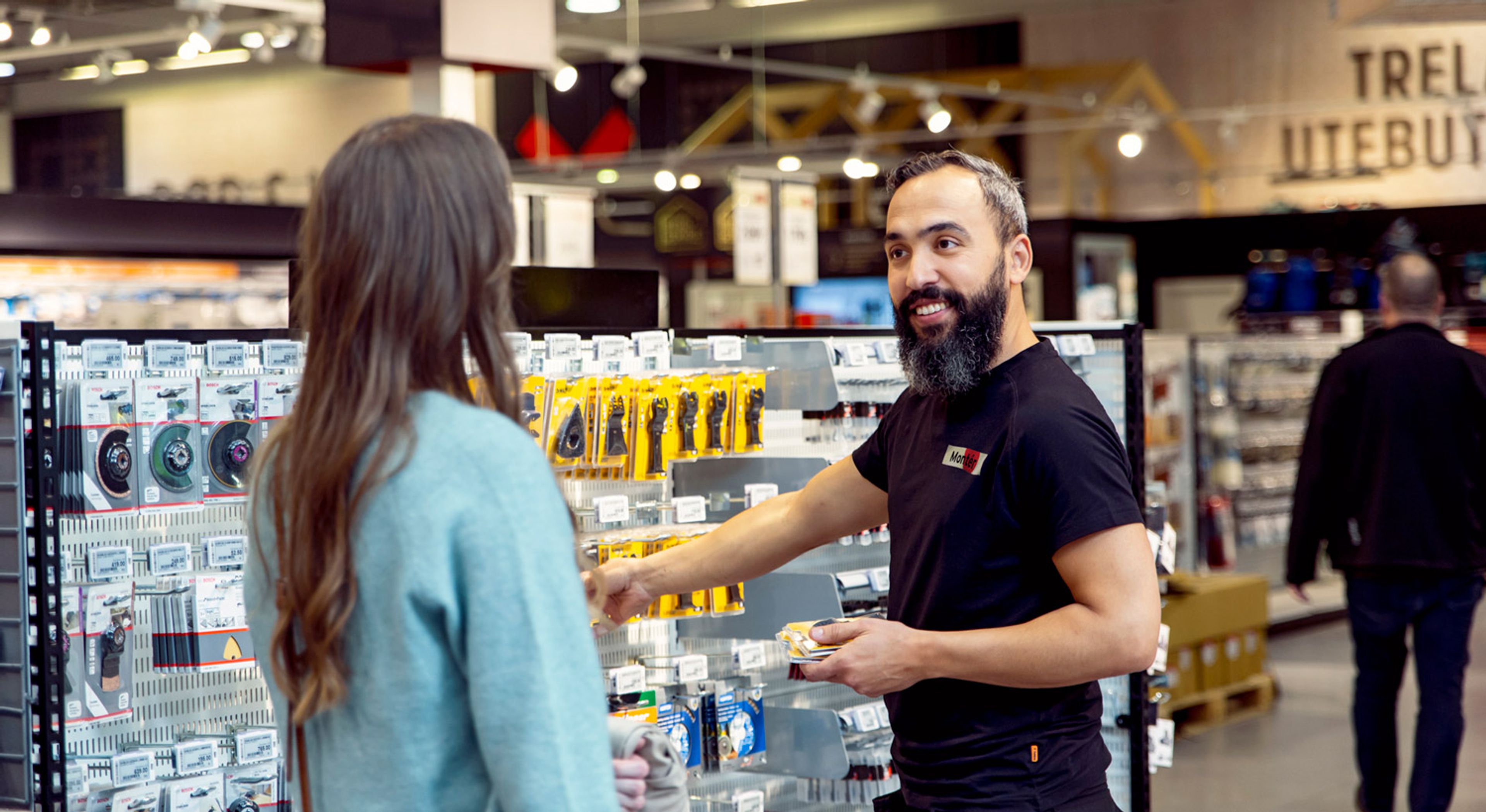 En mannlig ansatt i monter hjelper en kunde i butikken