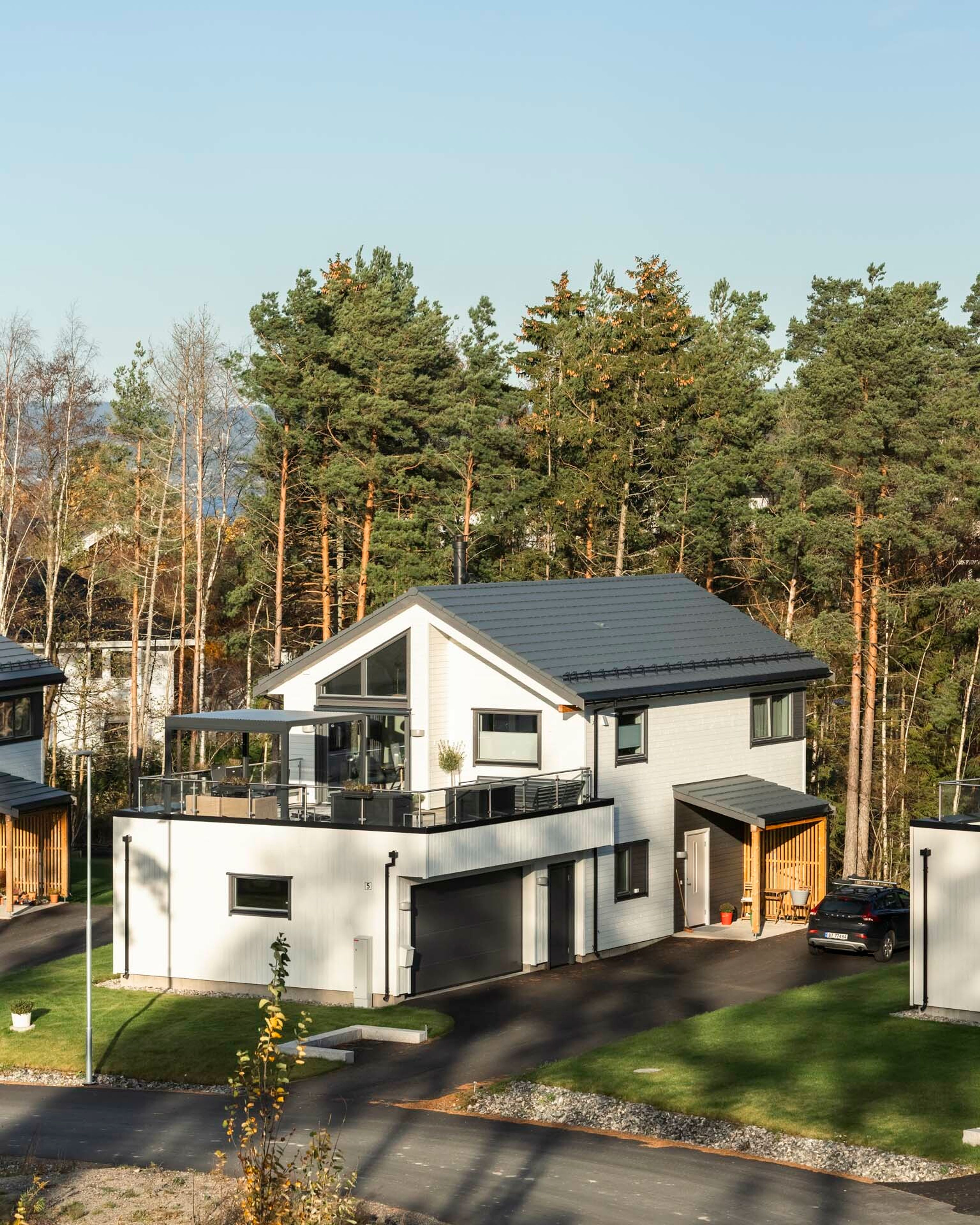Foto av hvit enebolig i OBOS Block Watne-prosjektet Villa Havblikk, med inngang, garasje og terrasse over garasjen.
