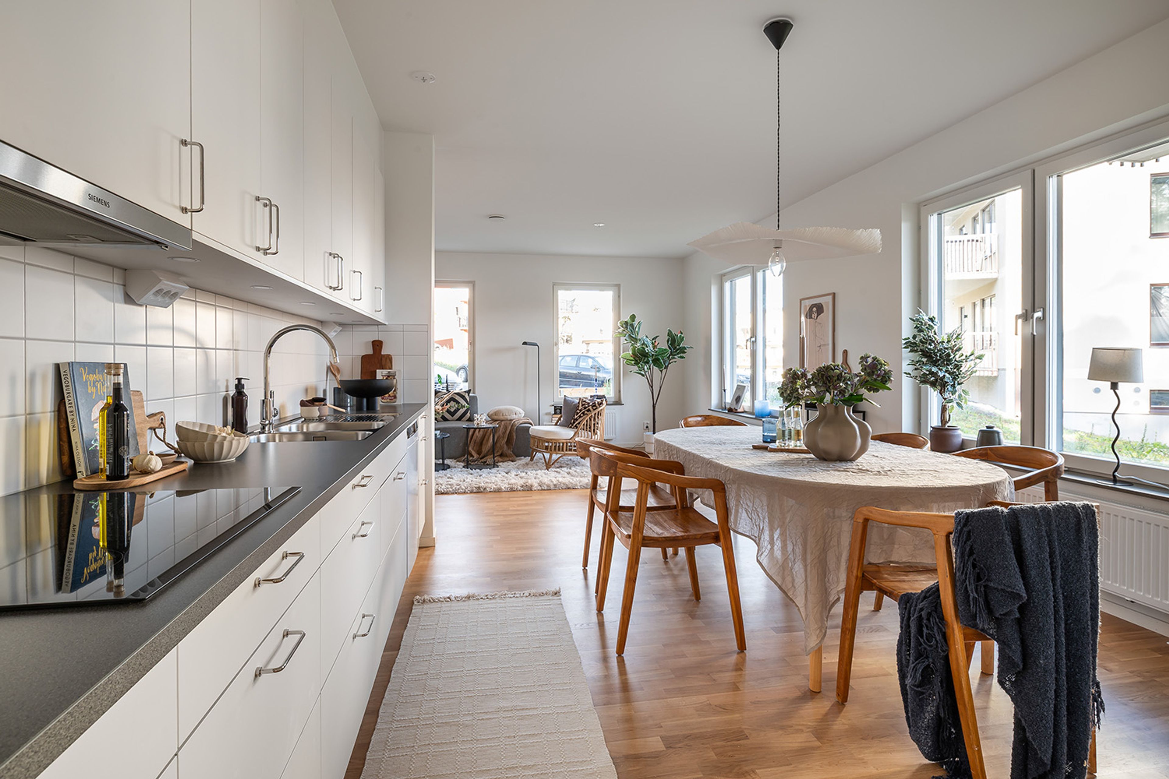 Foto på kök med stor matplats i anslutning till vardagsrum