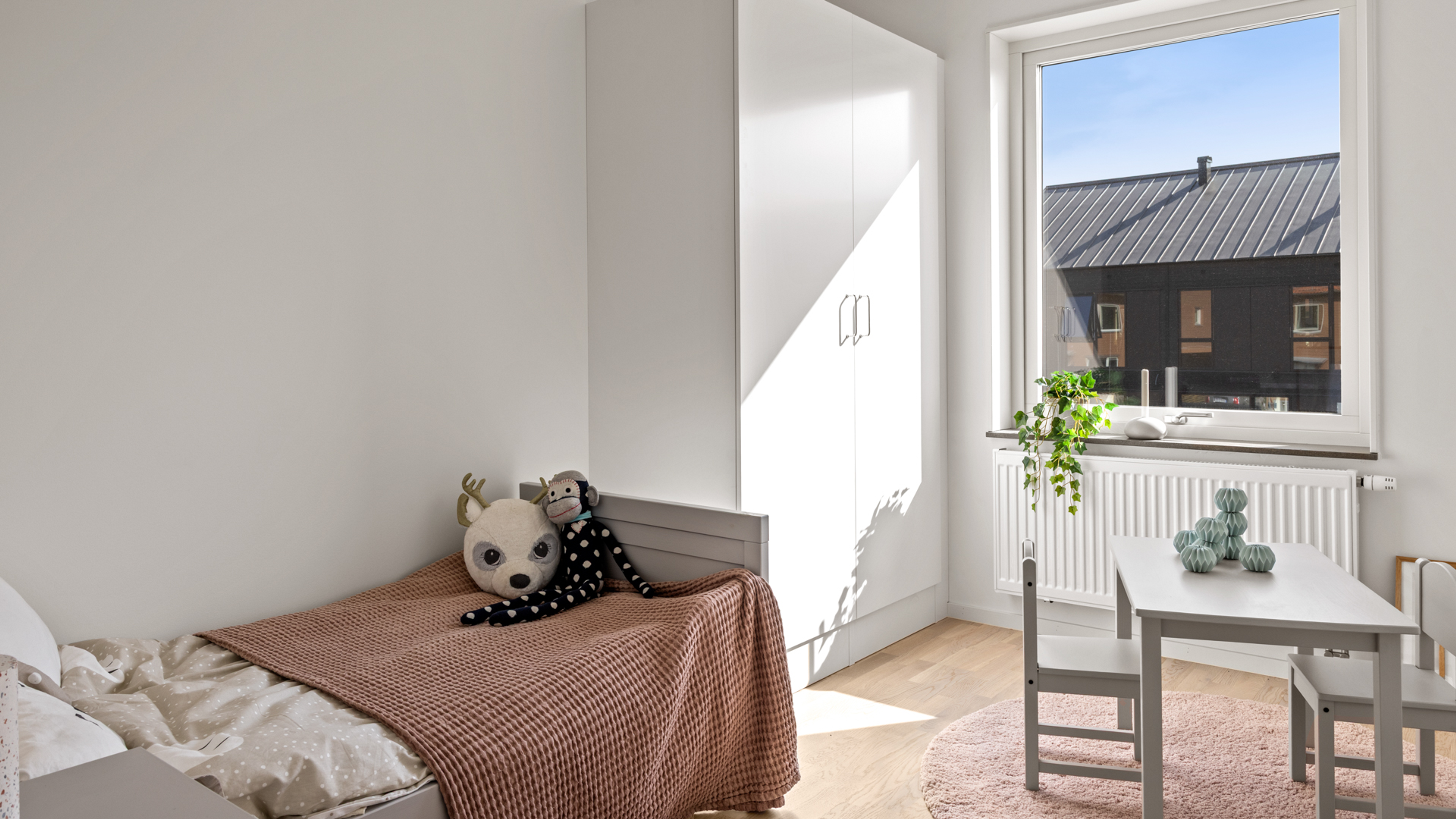 Barnrum på övervåning med enkelsäng och litet bord med 2 stolar