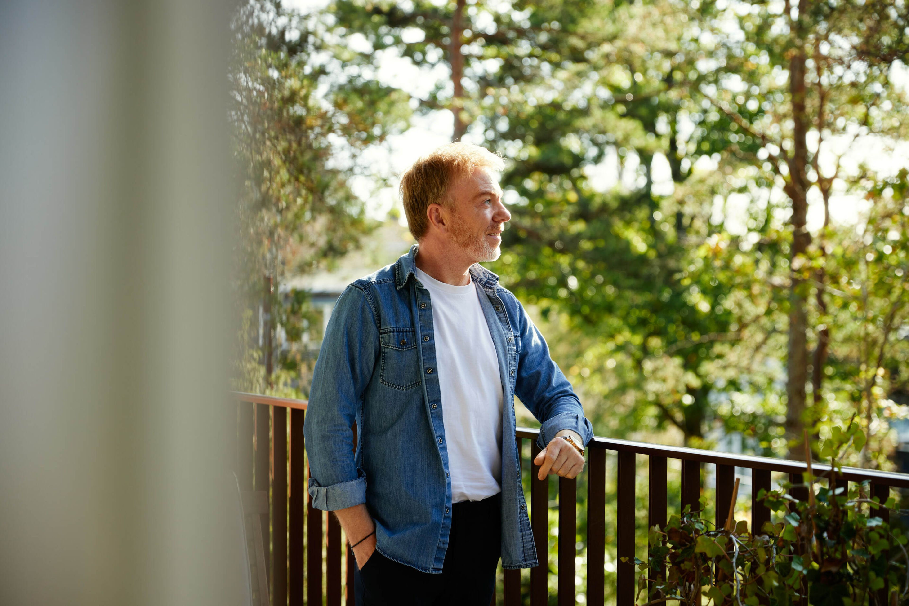 Espen står på verandaen i sin nye leilighet og ser utover skogen