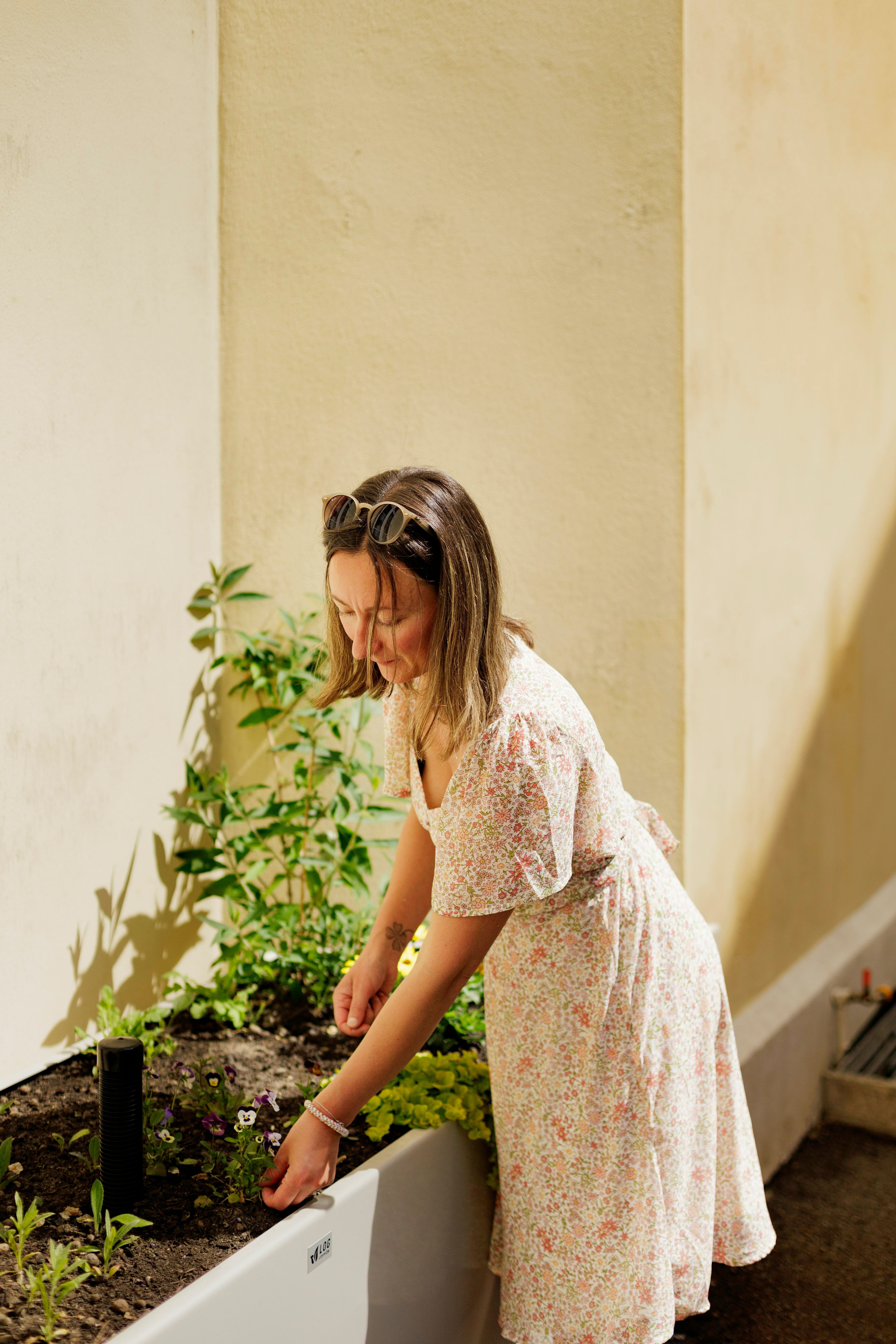 Styreleder Hanna Mari Hauan planter en ny plante i en av plantekassene i bakgården.