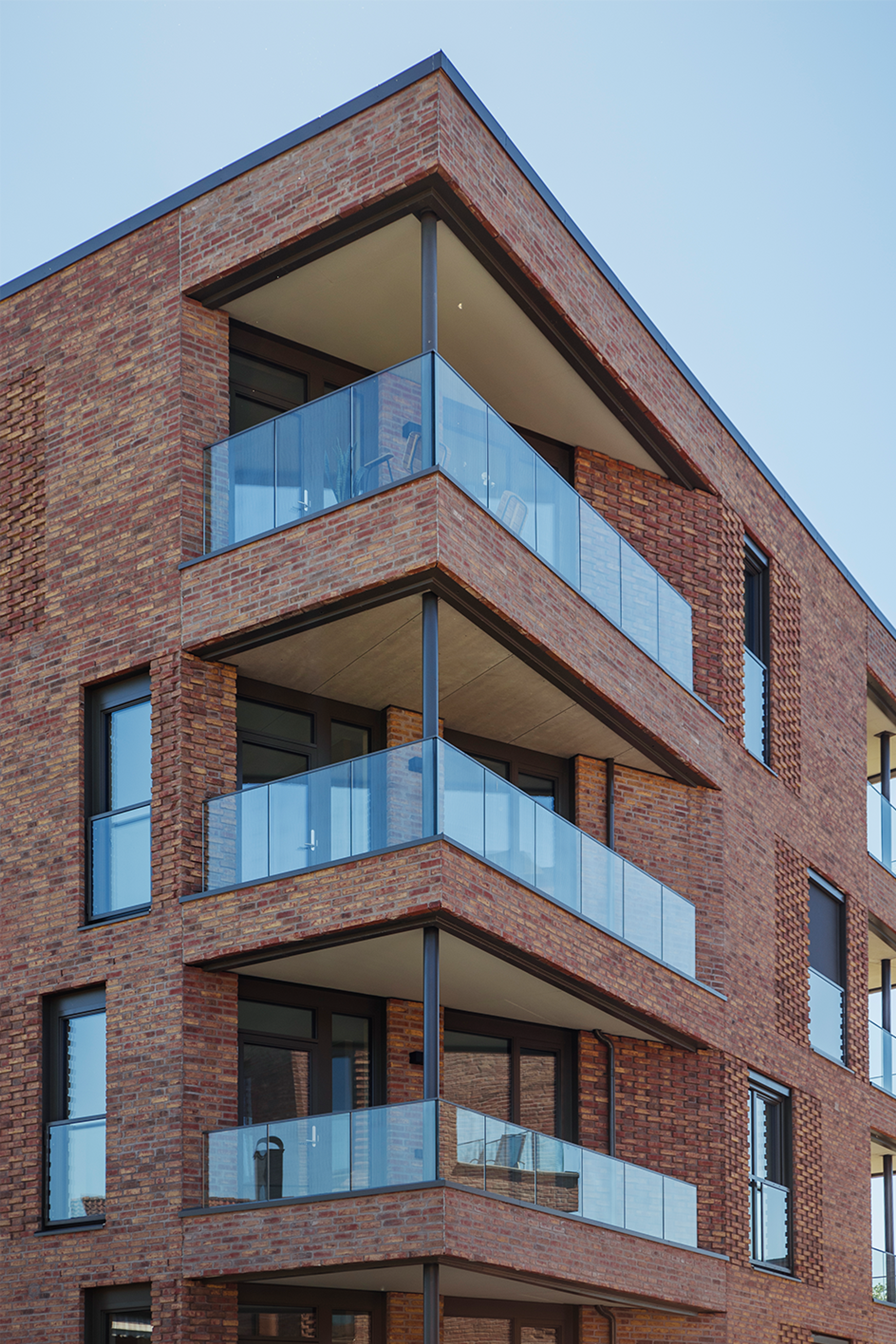 Bilde av en av blokkene i Hoffsveien Hage, fokusert på det ene hjørnet av blokken hvor tre store verandaer dominerer bygget.