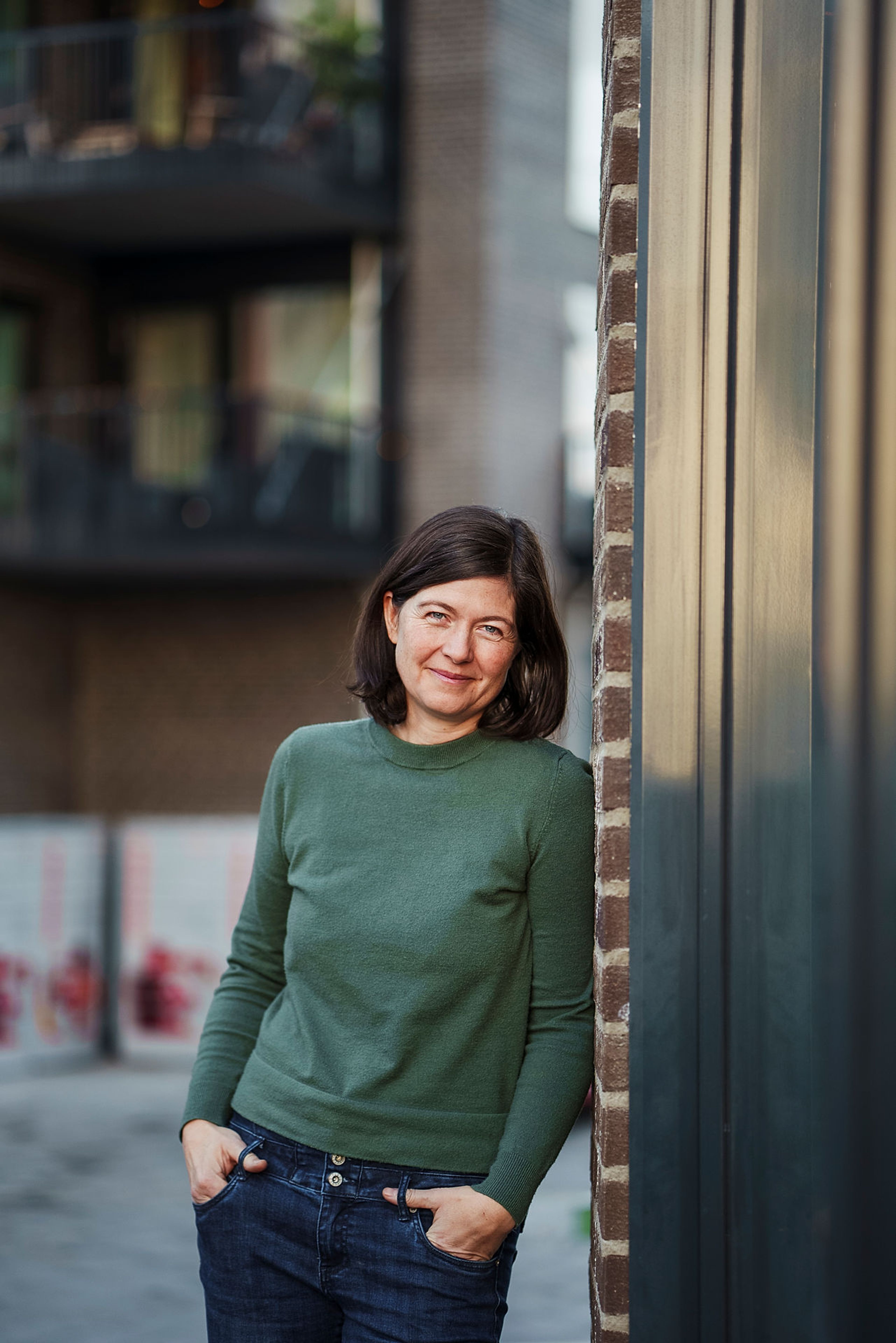 Nabolagsvert på Ulven, Katrin Schauer, lener seg mot en murvegg.
