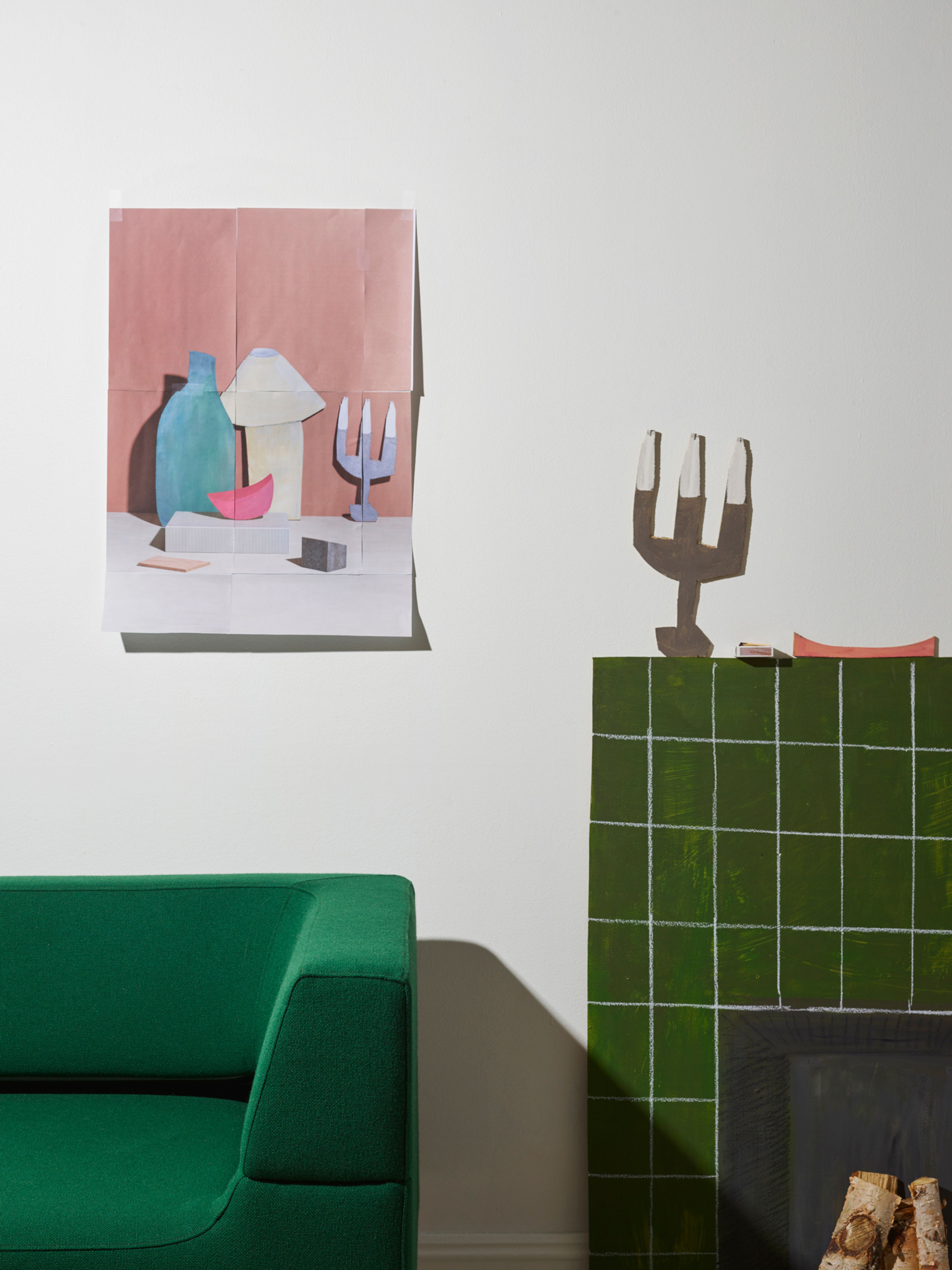 Grønn sofa, et bilde over sofaen. Peis og lysestake klippet ut i papir.