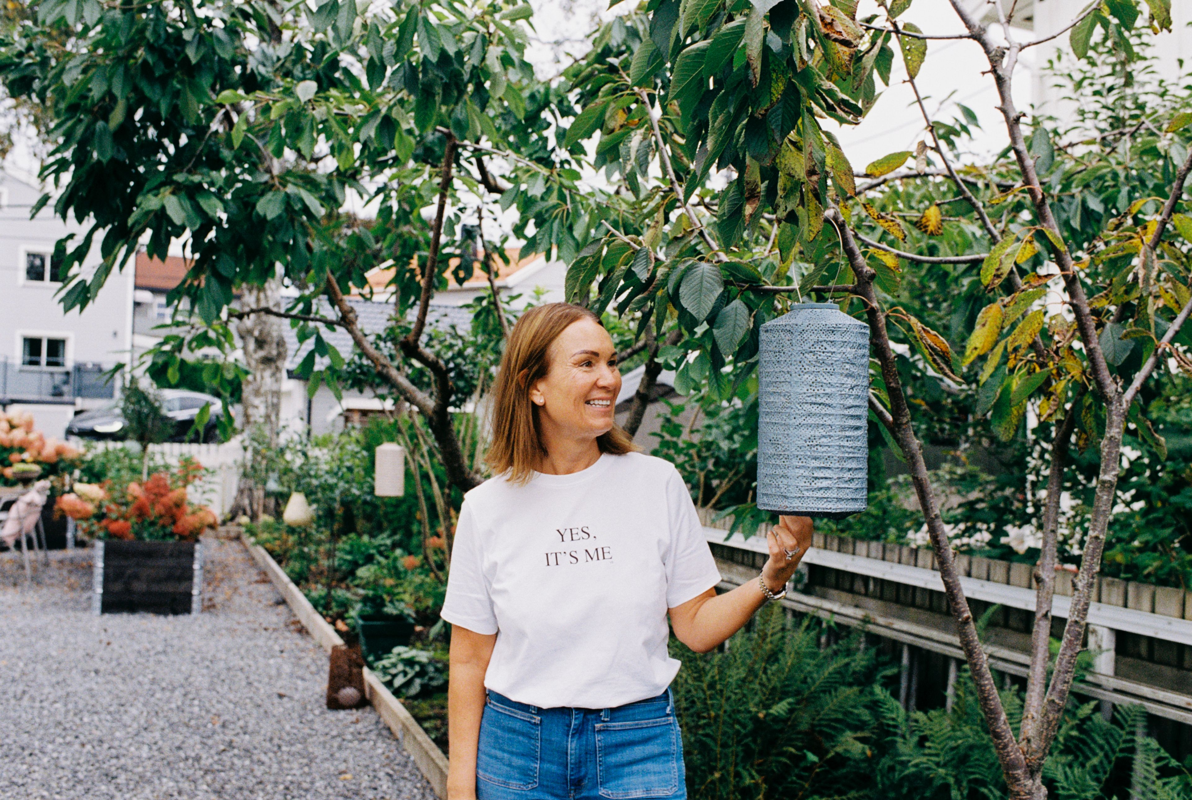 En smilende Camilla i profil i egen hage.