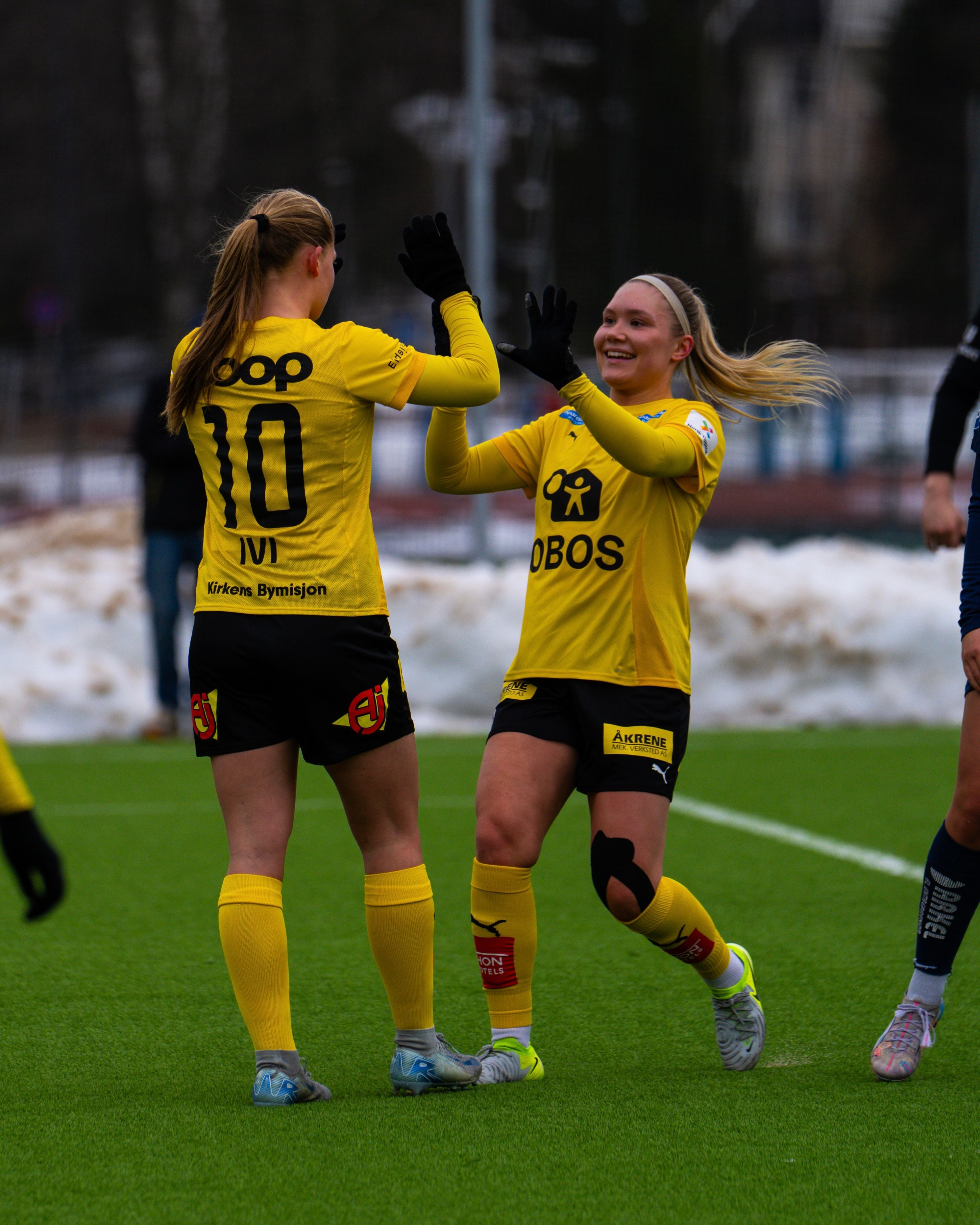 Foto av to LSK Kvinner spillere som tar high-five på banen.