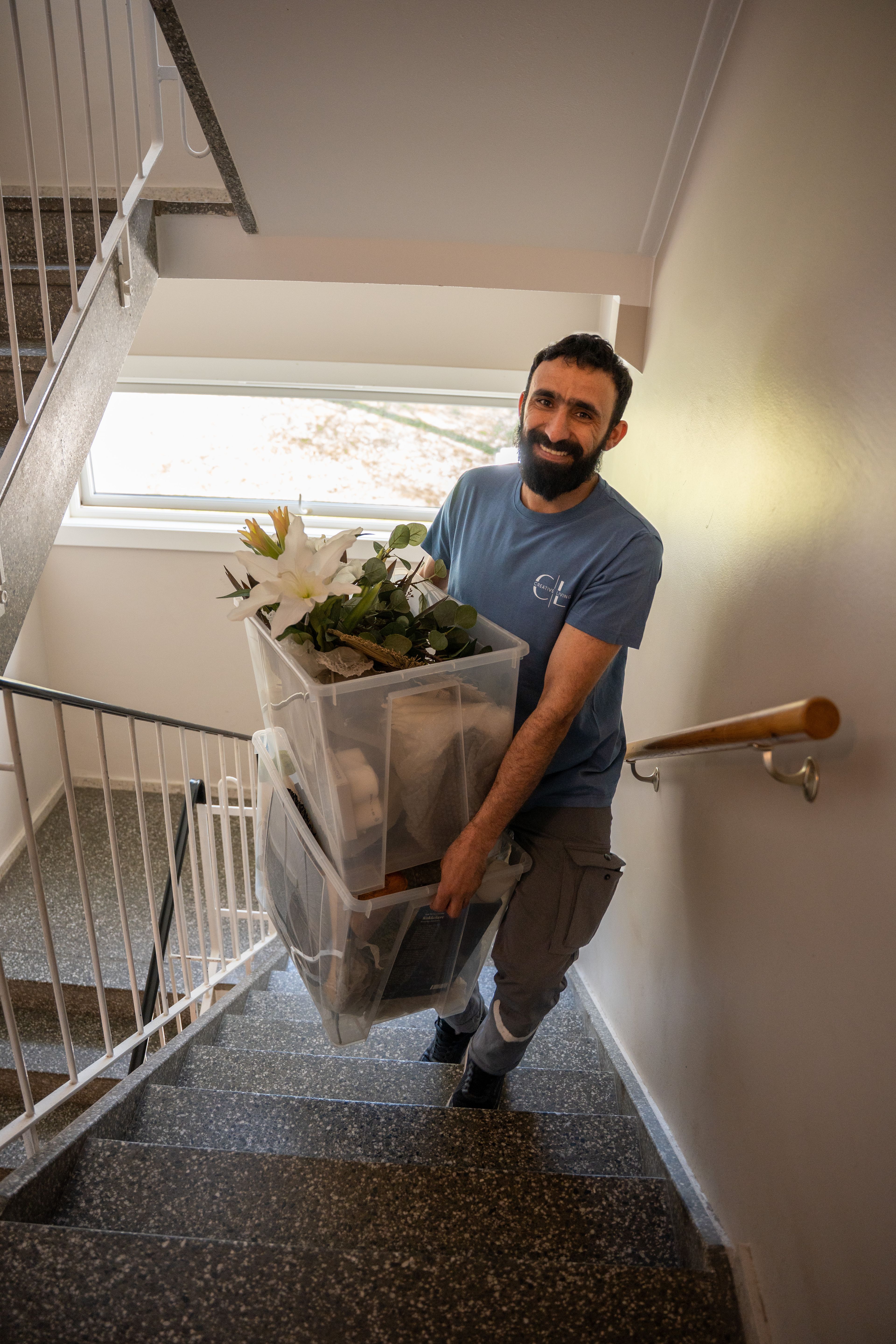 En mann bærer to kasser med interiør og blomster