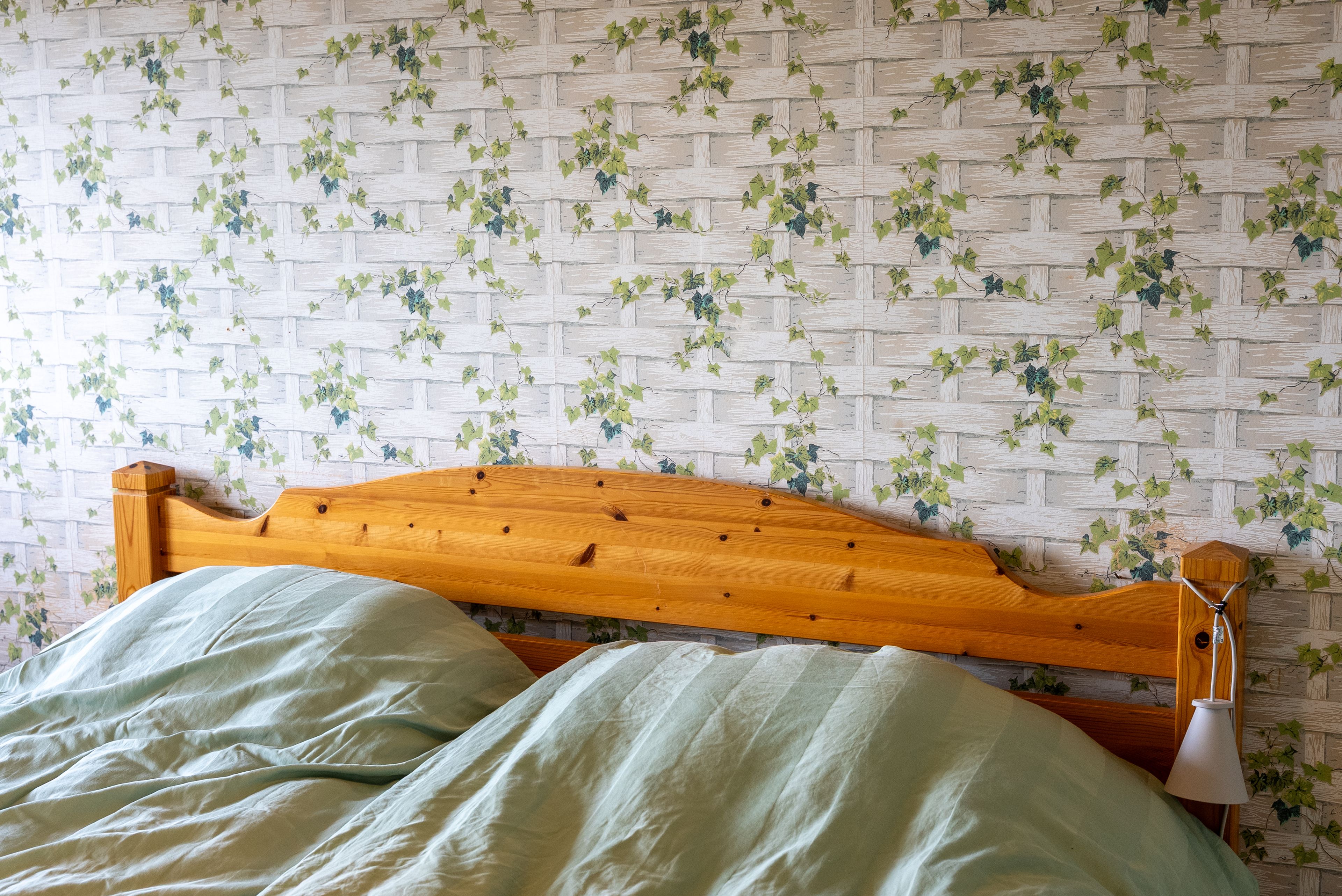 Eldre furuseng med blomstrete tapet bak