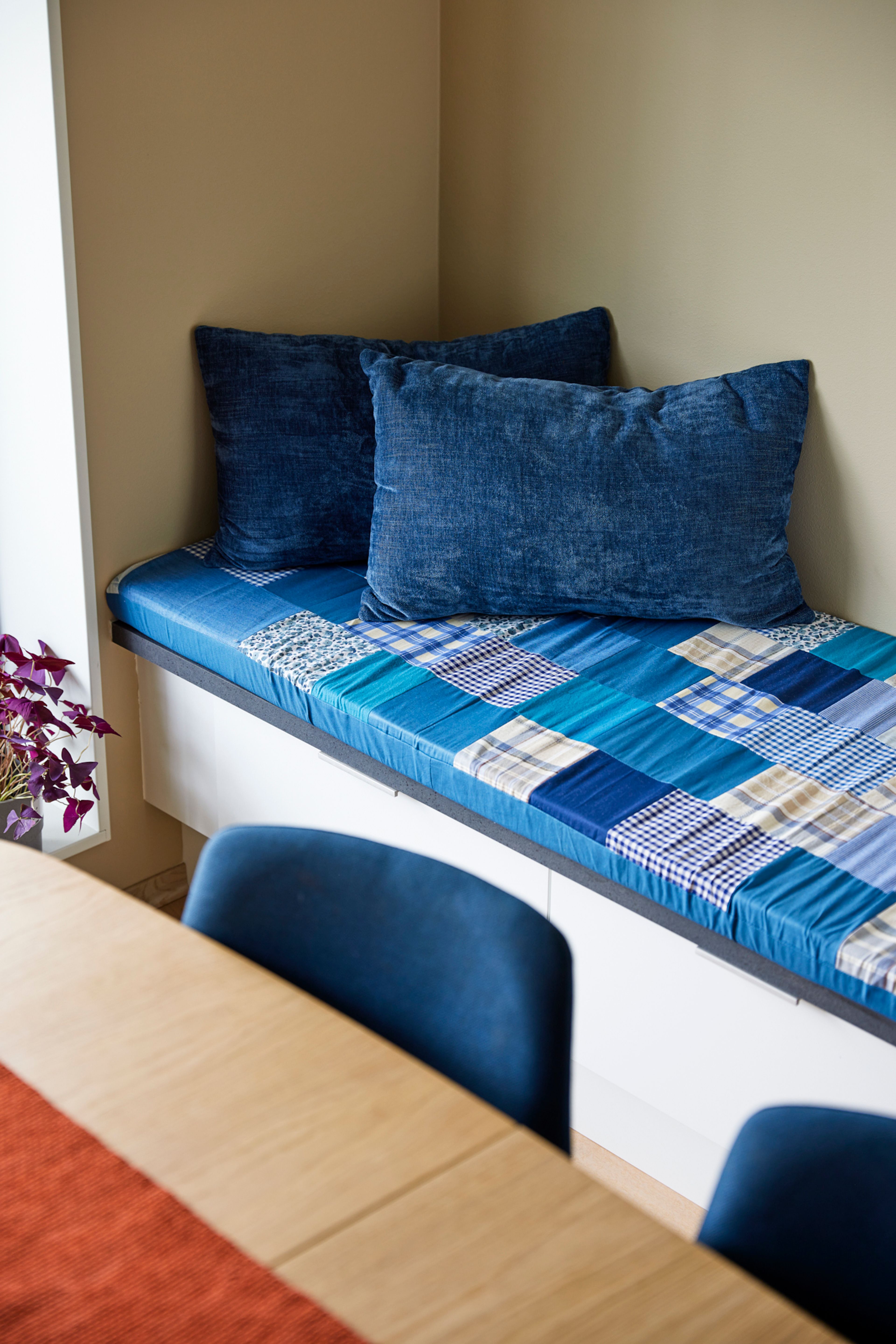 Detaljbilde av sittekrok på kjøkken med blå puter i.