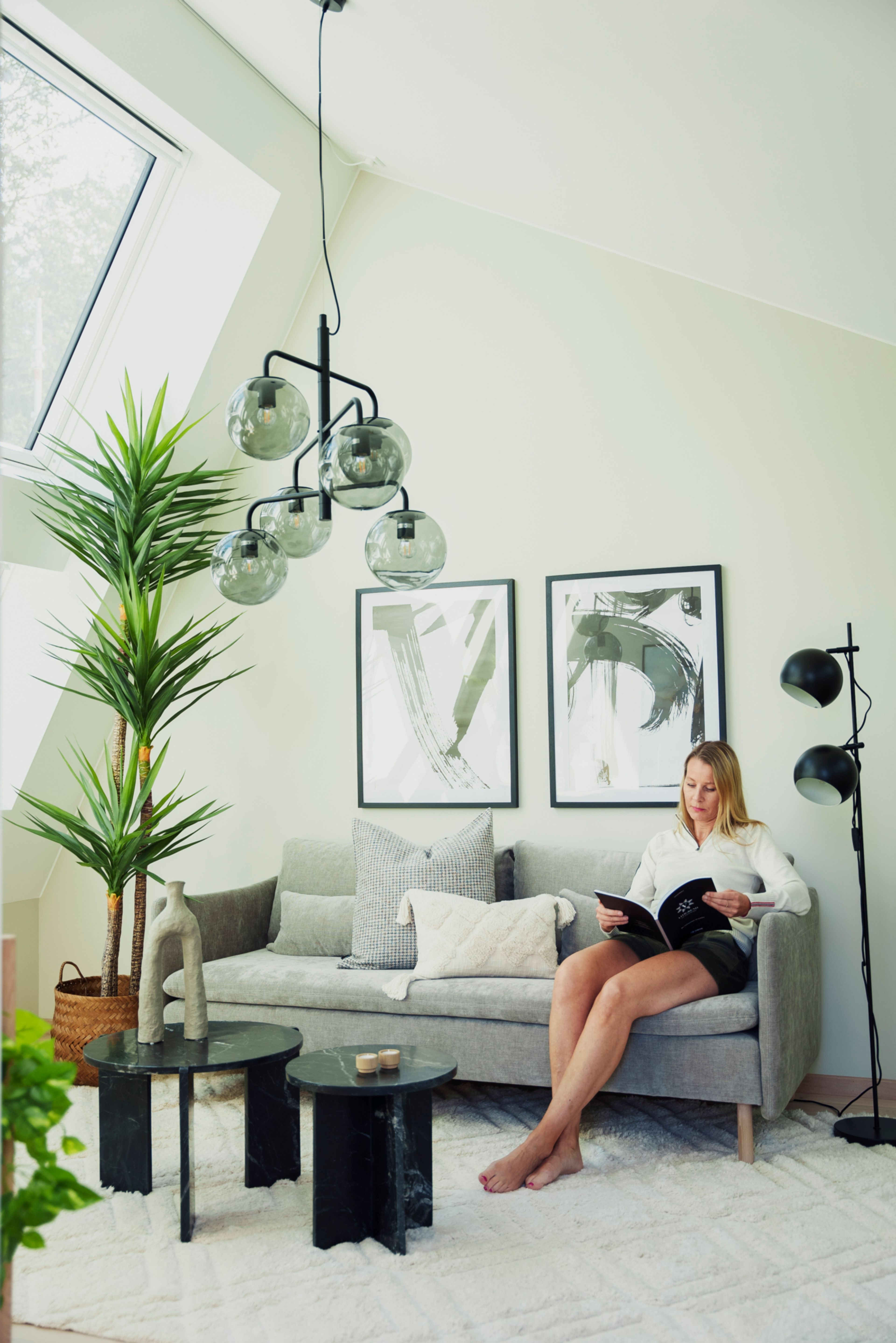 Kvinne som sitter i en grå sofa i en loftsstue