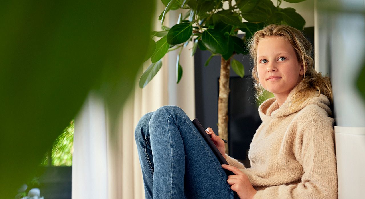 Foto av en ung jente som sitter på gulvet med en bok.