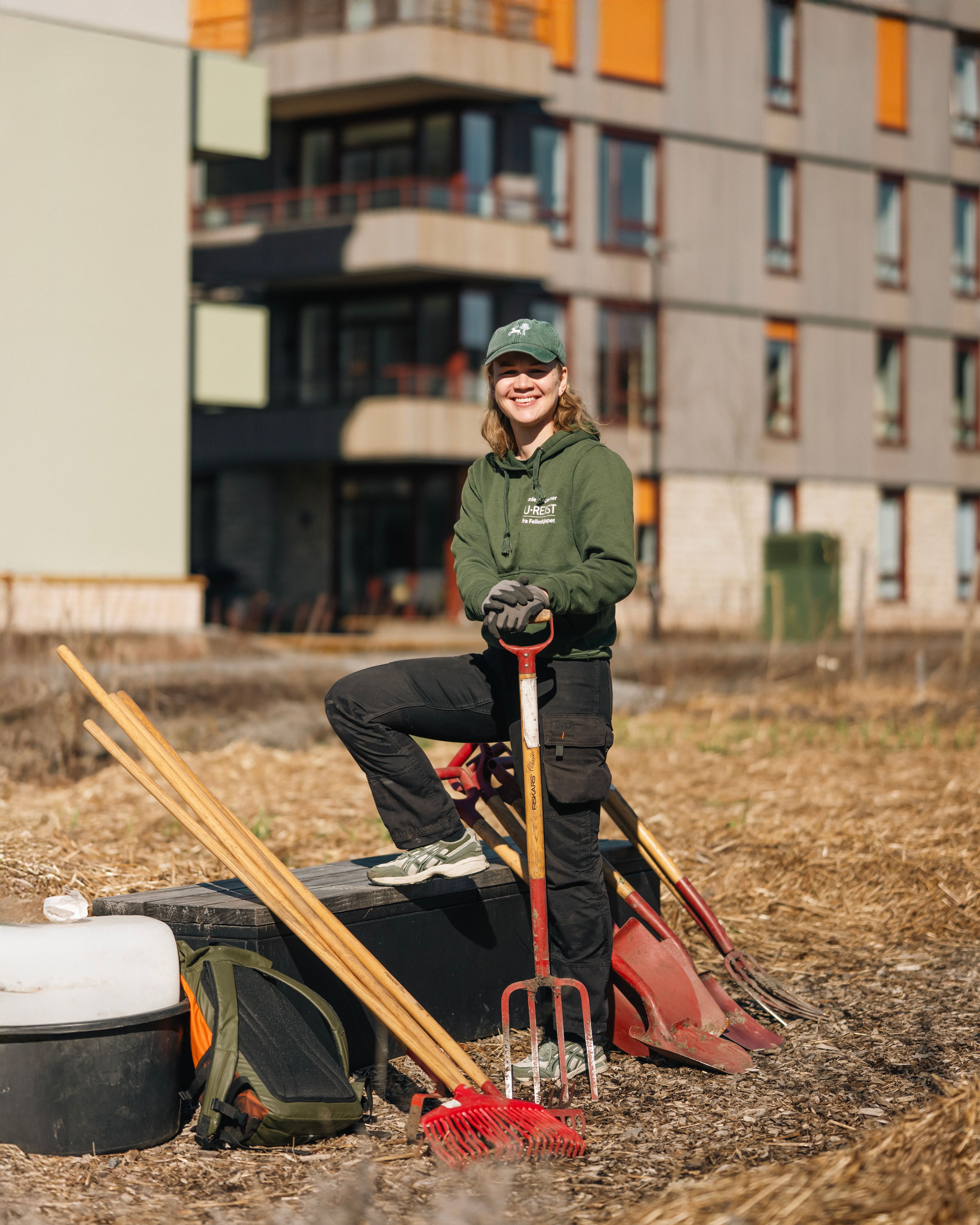 Bildet av Bybonde Frida Rygh de Flon med hageredskaper foran blokkene i Kvarteret.