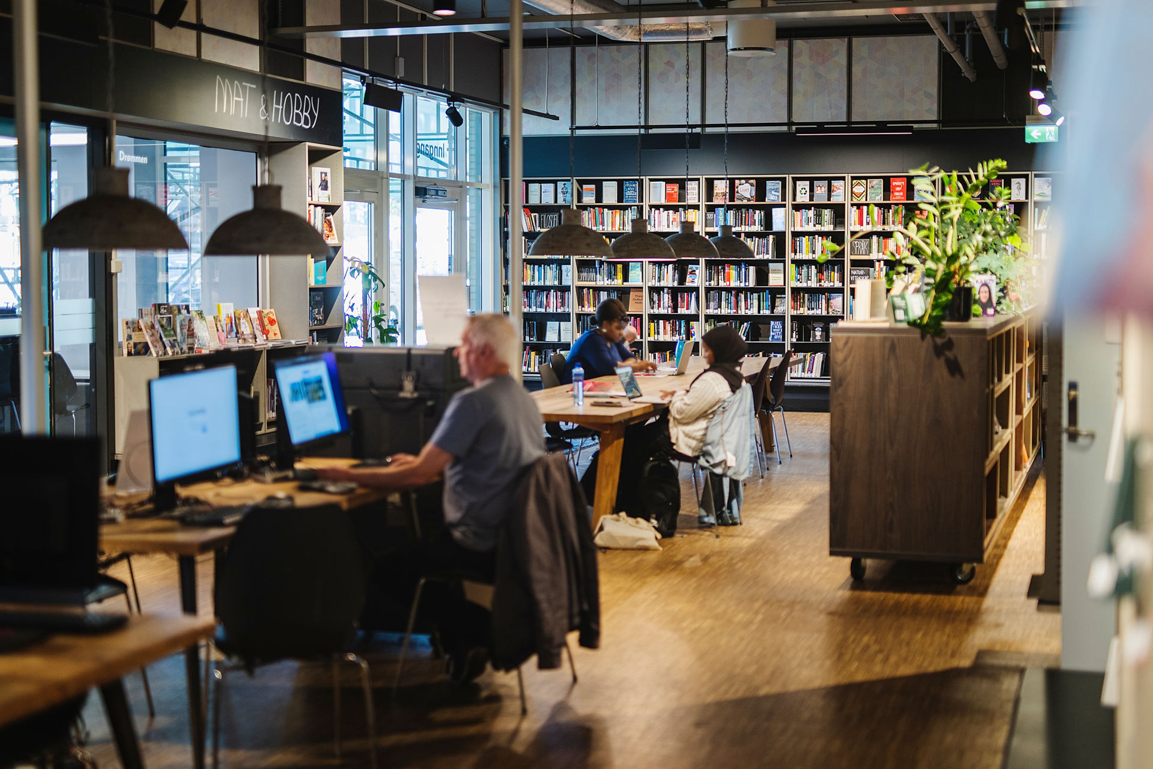 Mennesker inne på Furuset bibliotek og aktivitetshus.