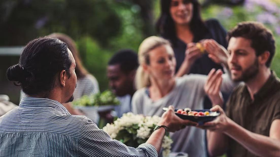Människor äter ute i trädgården