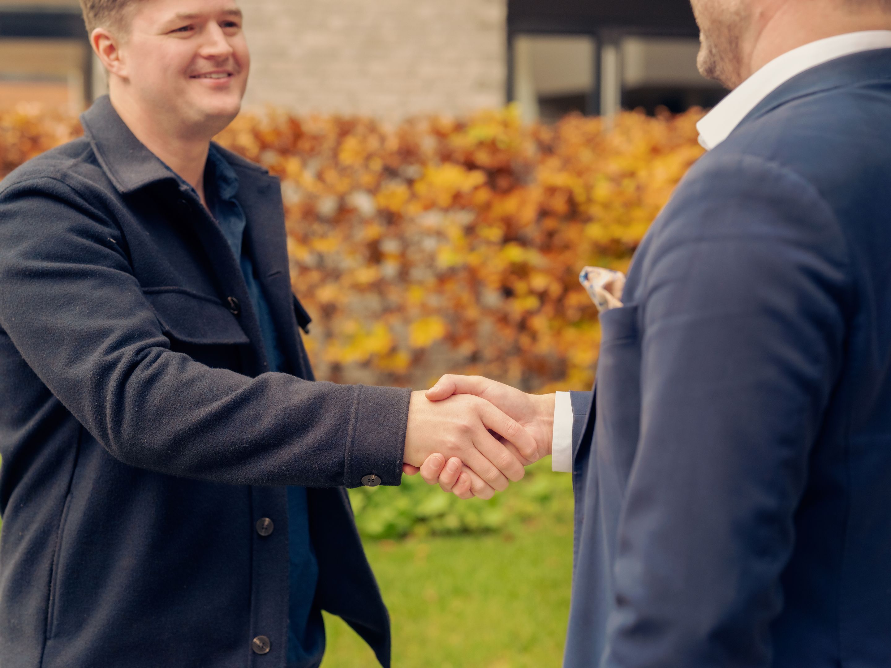 En megler og en kunde som gir hverandre et håndtrykk etter et boligsalg. 