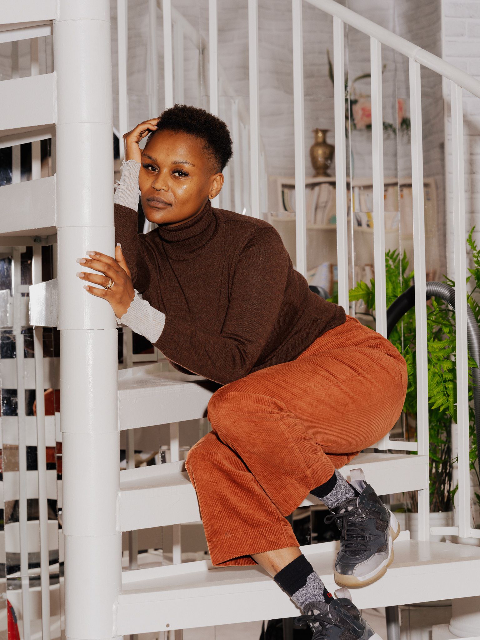 Jae Nyamburah sitter i en hvit trapp og lener seg inn mot rekkverket.