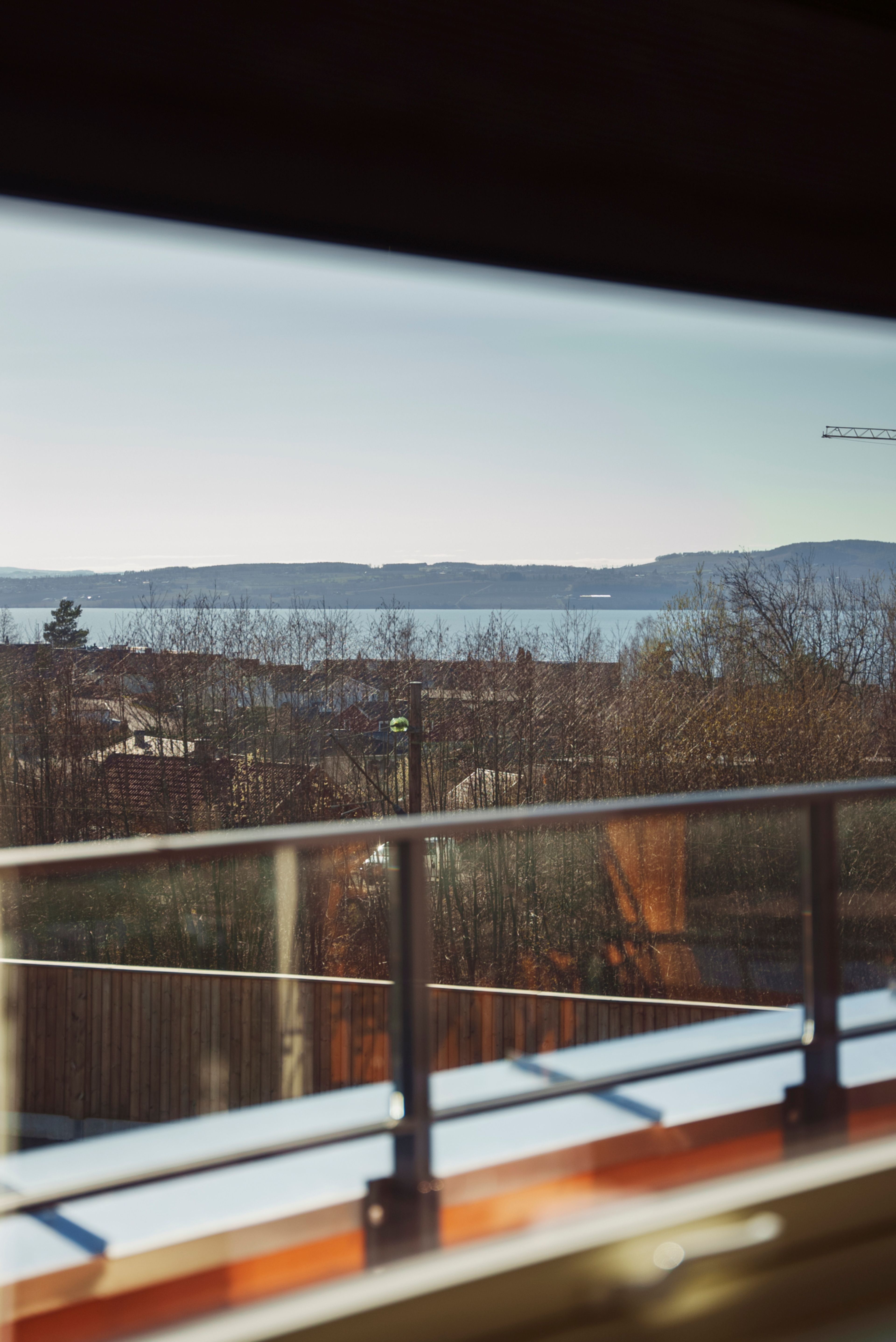 Utsikt over Mjøsa fra vinduet til rekkehuset på Sandviksløkka, tatt innenfra. Ute er det sol og fint vær.