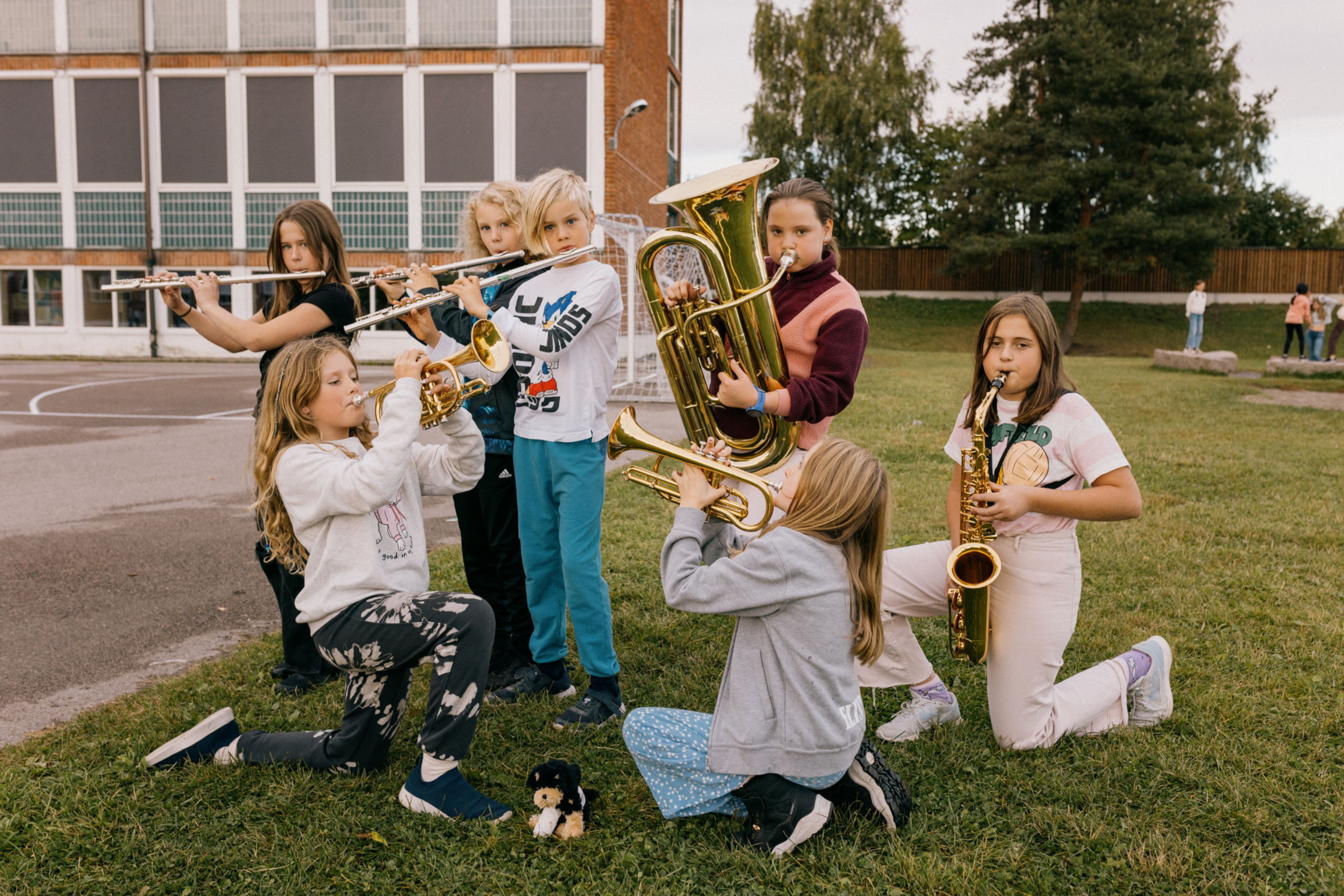 Noen av de unge musikantene i Lillestrøm skolekorps spiller på instrumentene sine utendørs.
