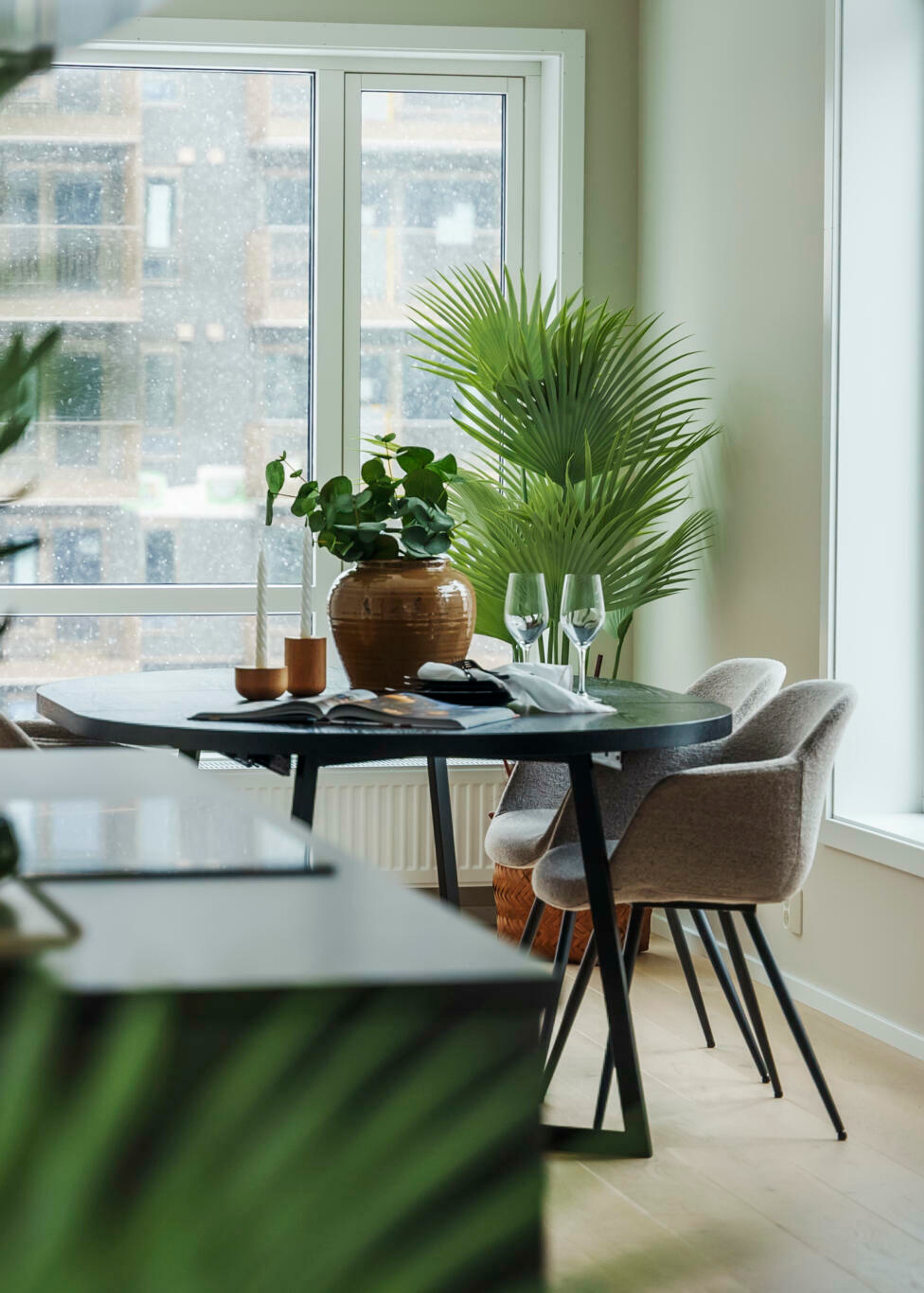 Sort spisebord med lyse velur stoler og grønne planter i MIDT.