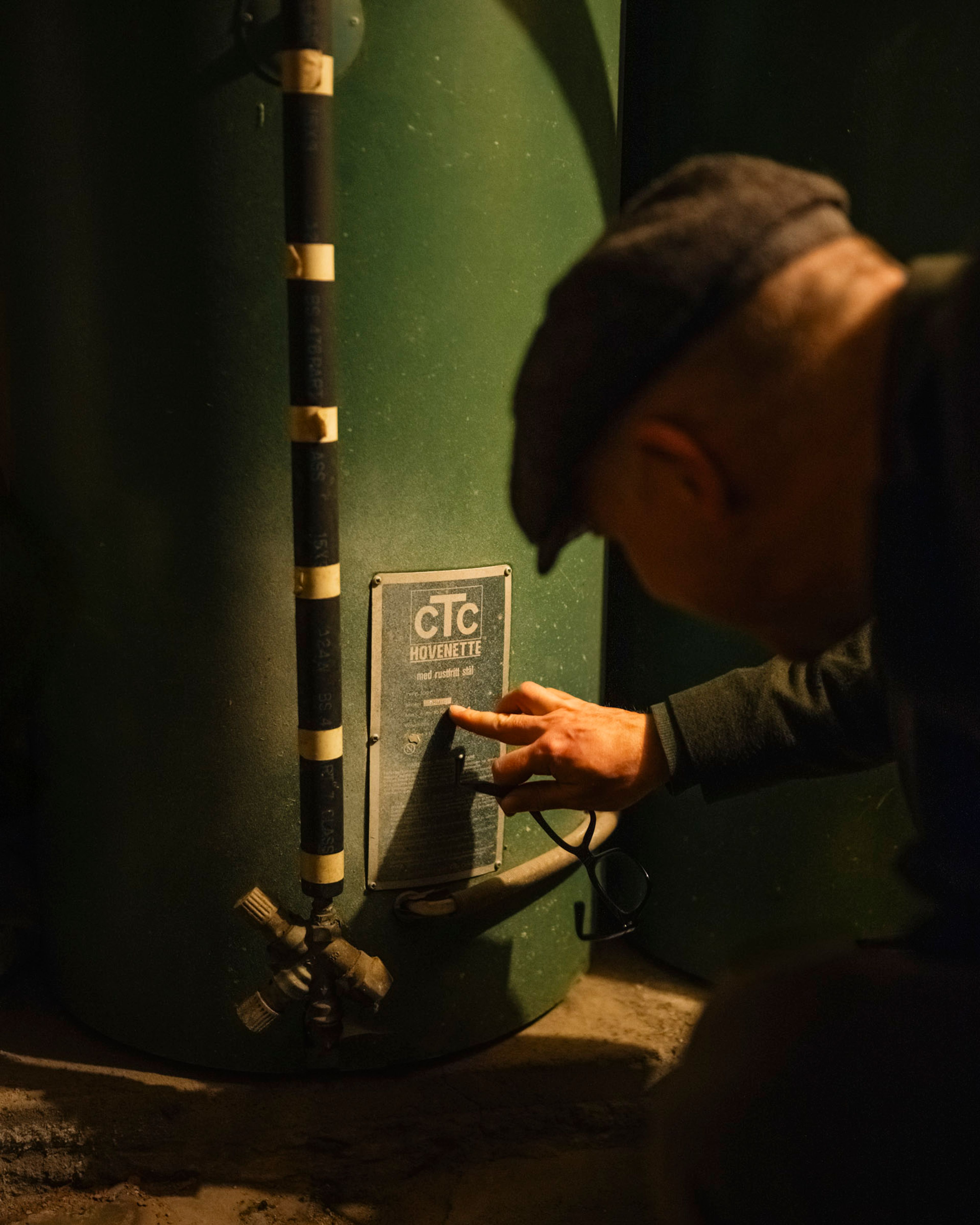 Styreleder Frank Martinsen undersøker det eksisterende varmtvannsanlegget i kjelleren i Markveien 2.