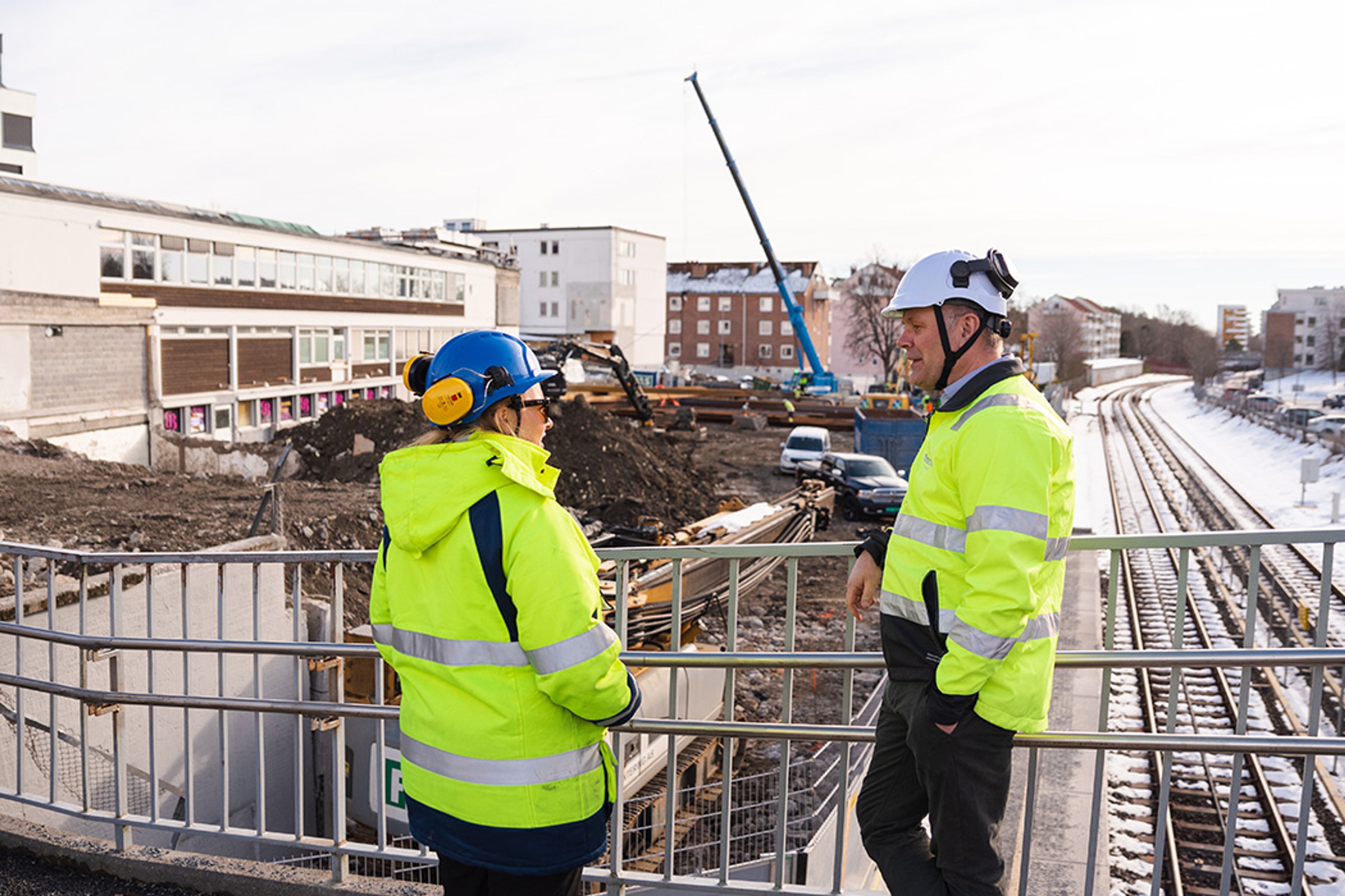 Foto av to bygningsarbeidere ved byggeplassen til Lambertseter Senter Sør.