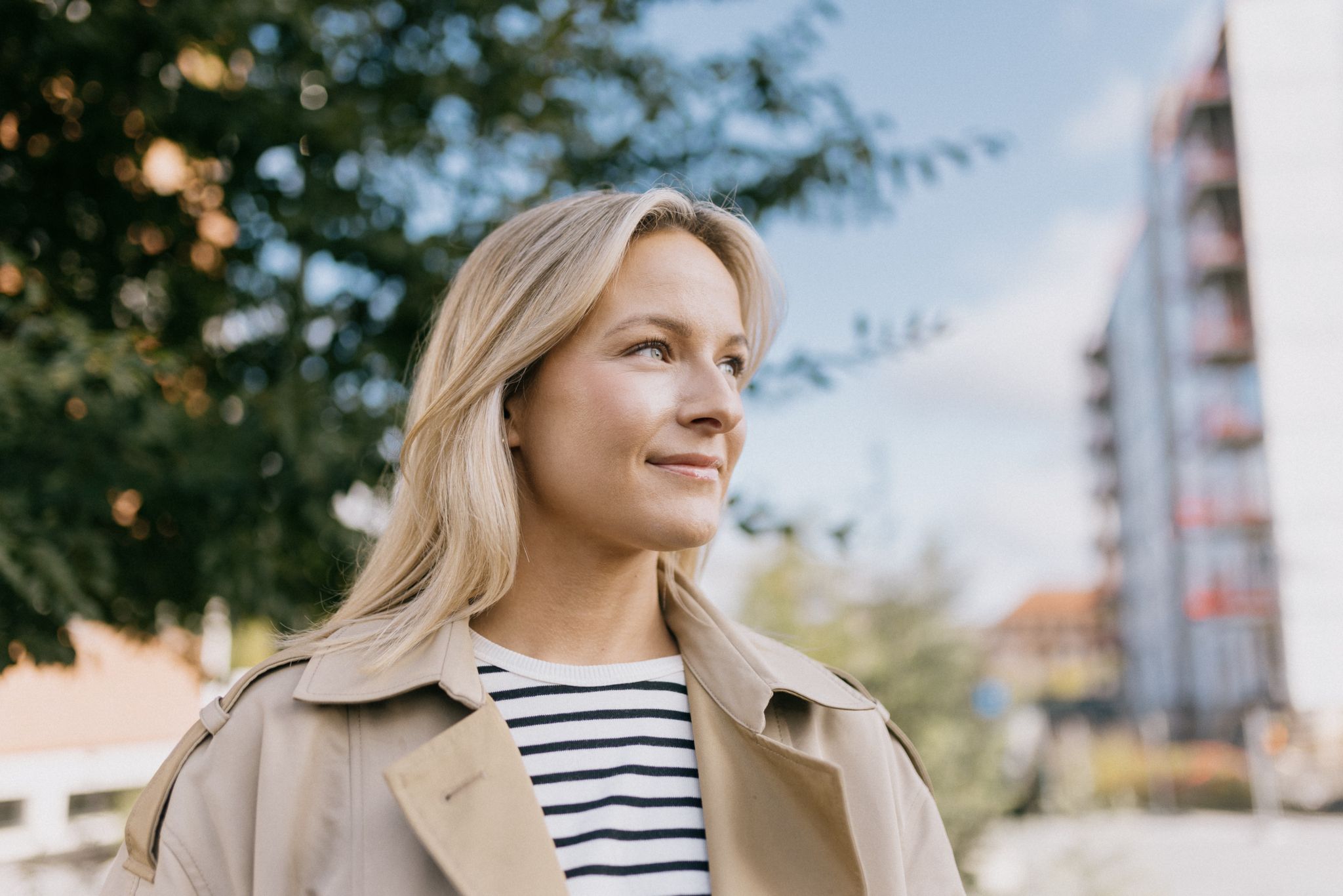 Foto av Brita som står foran byggeområdet på Ulven hvor hun har kjøpt seg leilighet