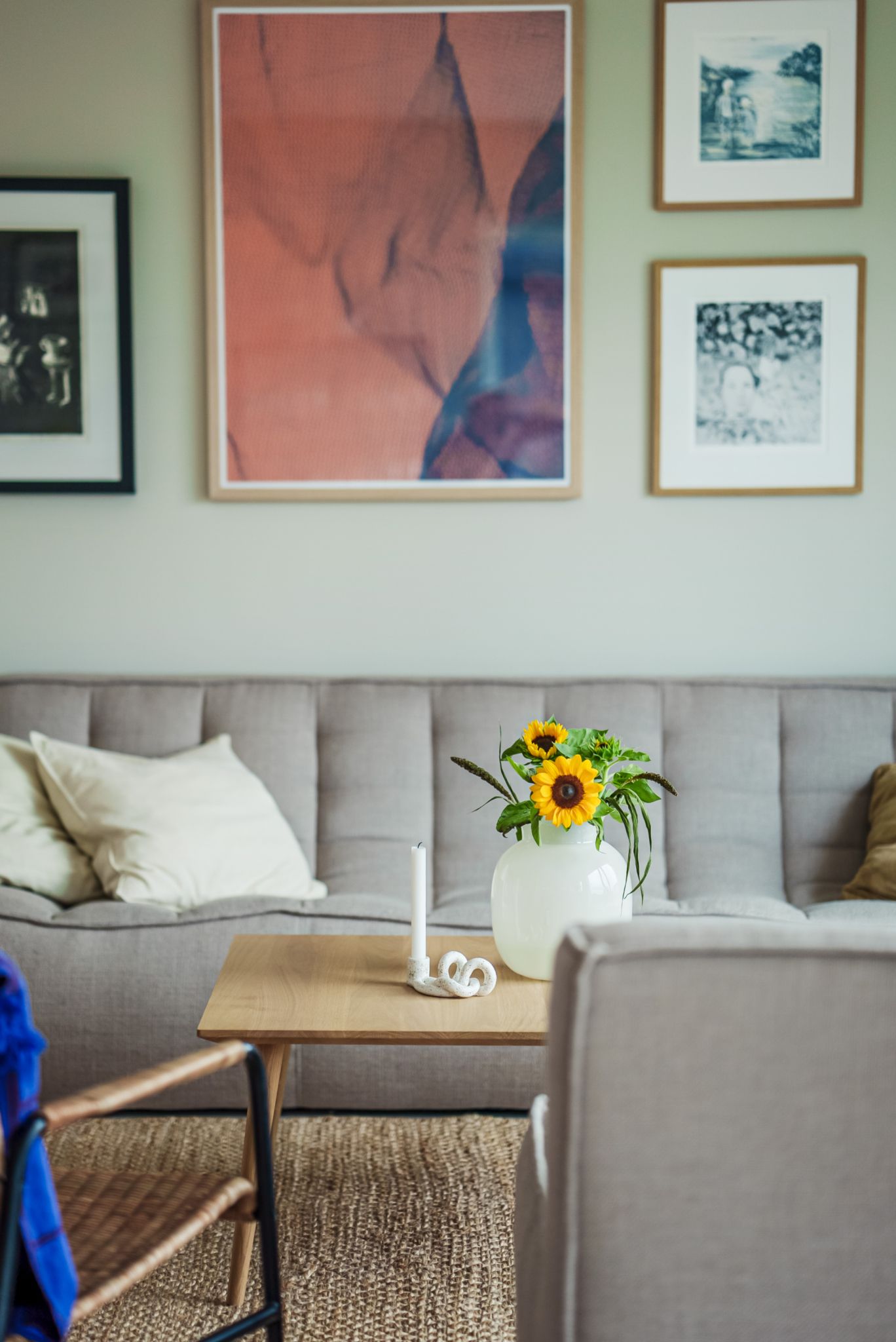 Deler av stuen i huset, med sofa, sofabord og bildevegg bak sofaen.
