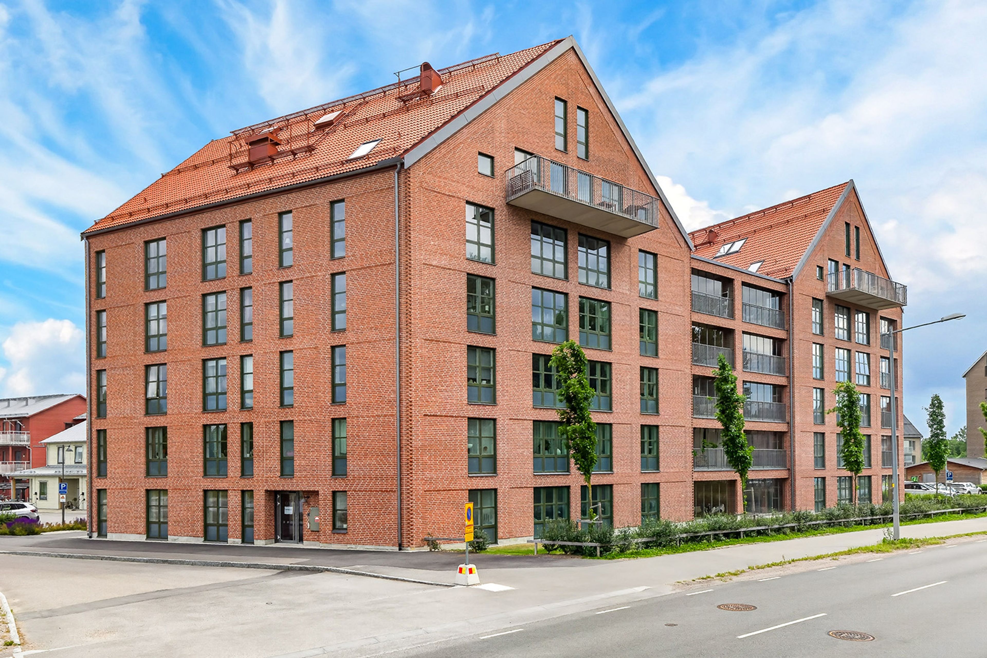 Foto på ett lägenhetshus med rött tegel och fabriksstil på fönstren