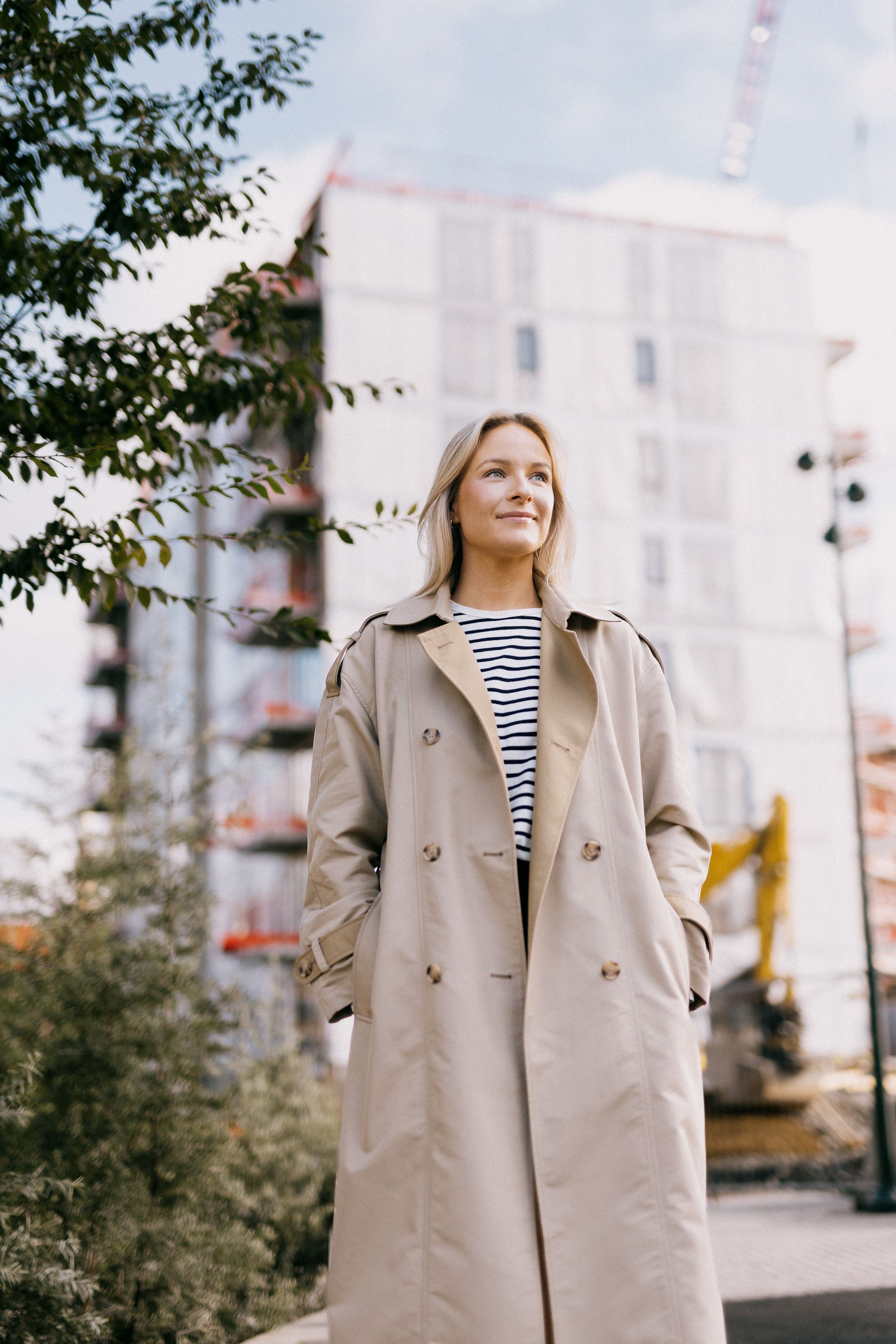 Foto av Brita som står foran byggeområdet på Ulven hvor hun har kjøpt seg leilighet