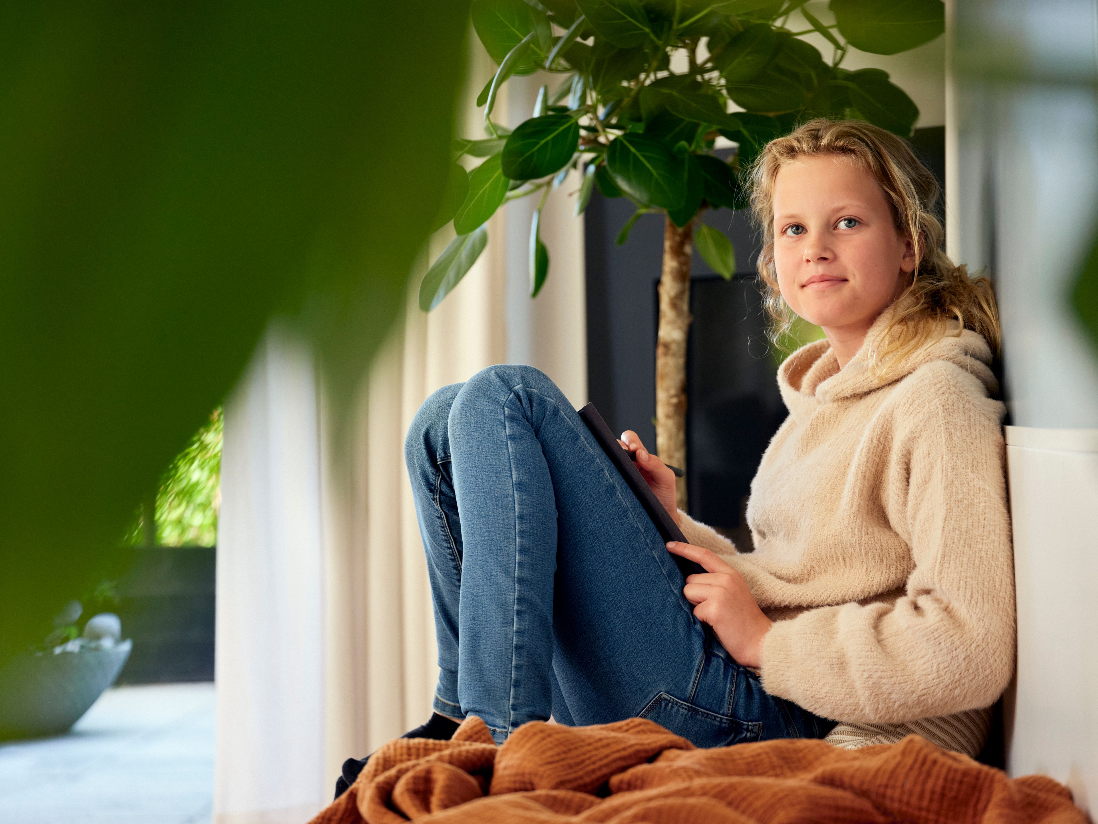 Foto av en ung jente som sitter på gulvet med en bok.