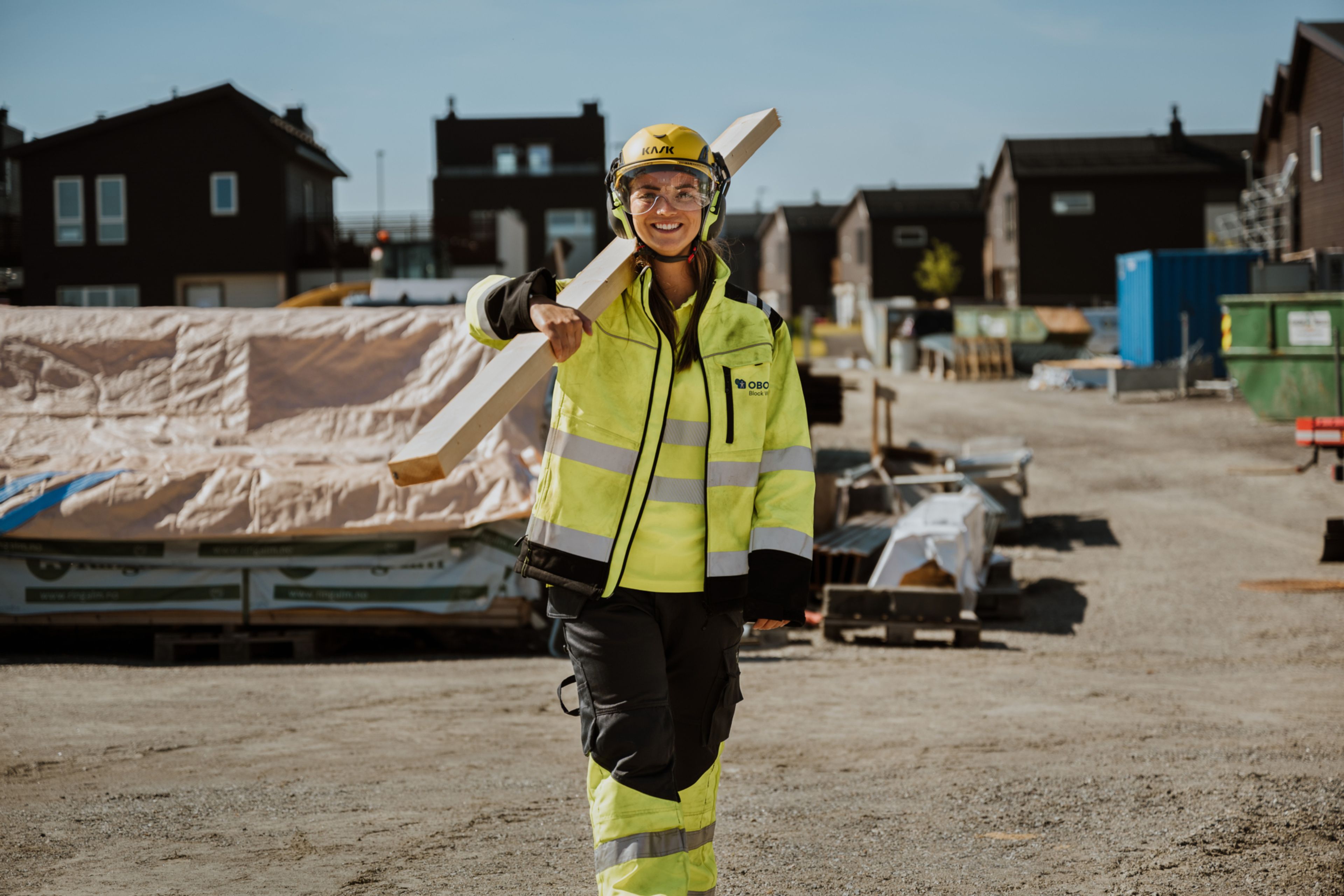 Ei tømrer bærer på planker i verneutstyr på Løkenåsen. Her bygger OBOS Block Watne eneboliger i kjede.