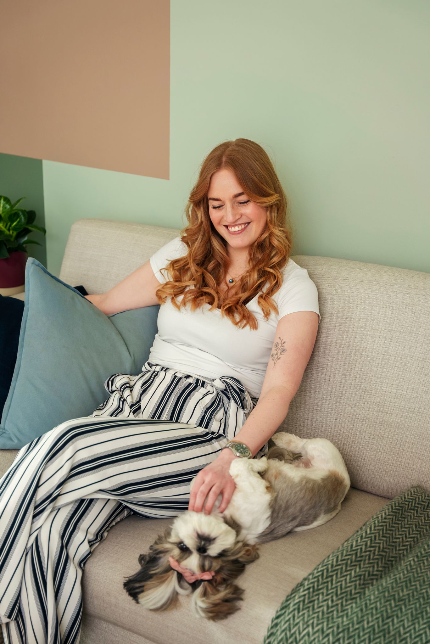 Hanne Rammen og hunden Emily sitter i en sofa, mens Hanne klør Solveig på magen.