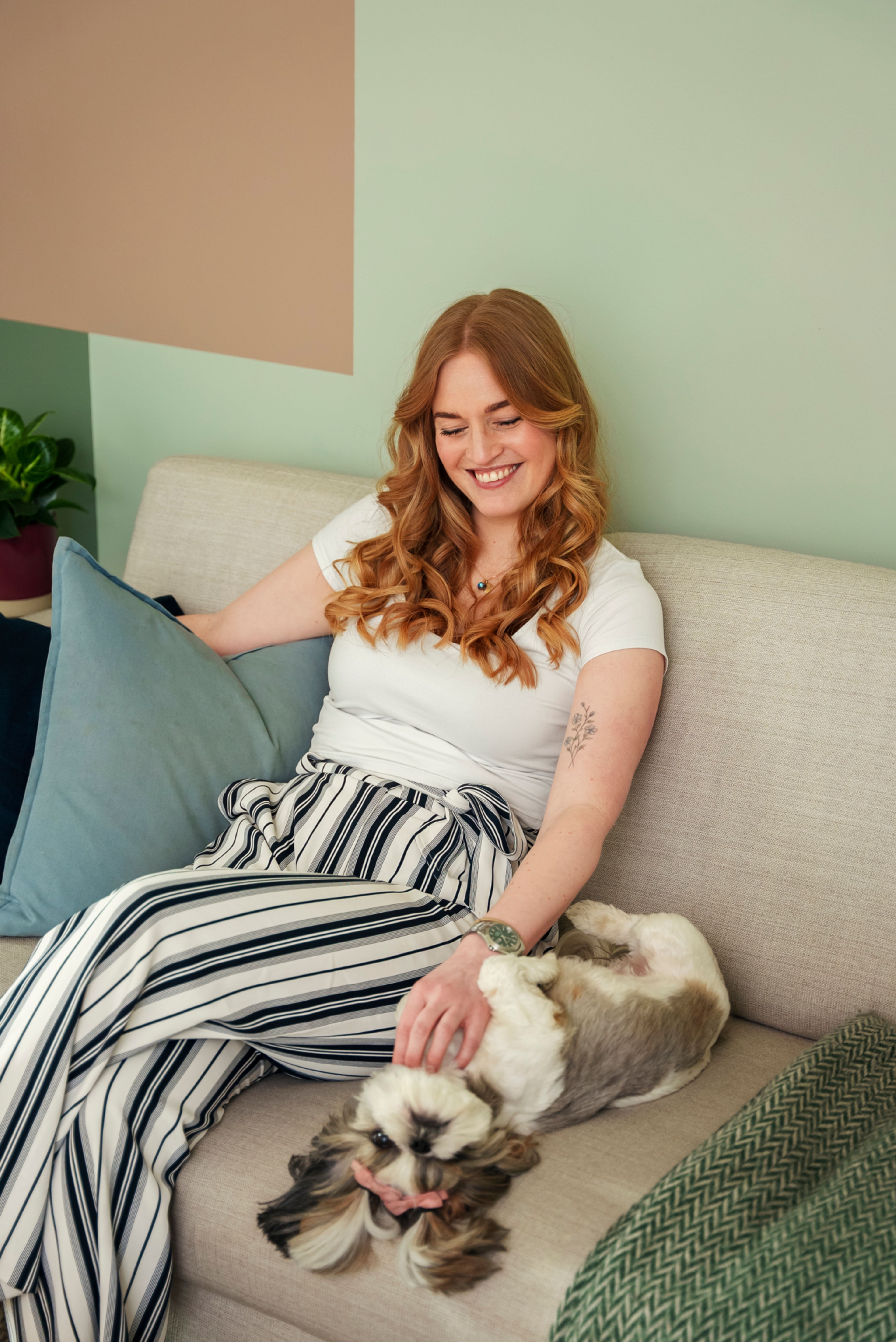 Hanne Rammen og hunden Emily sitter i en sofa, mens Hanne klør Solveig på magen.