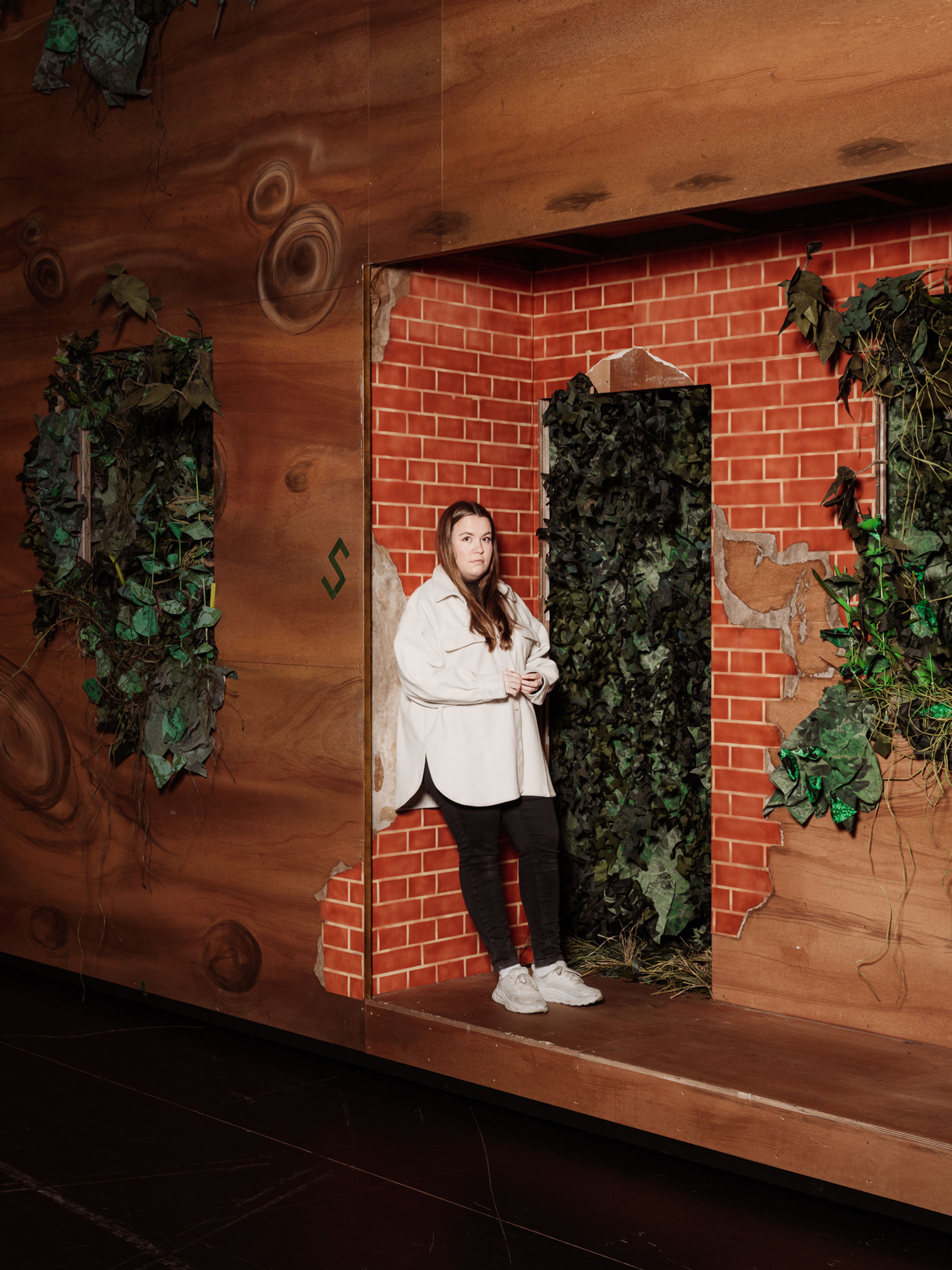 Ina Svenningdal lenar seg mot ein vegg i Into the woods-kulissane.