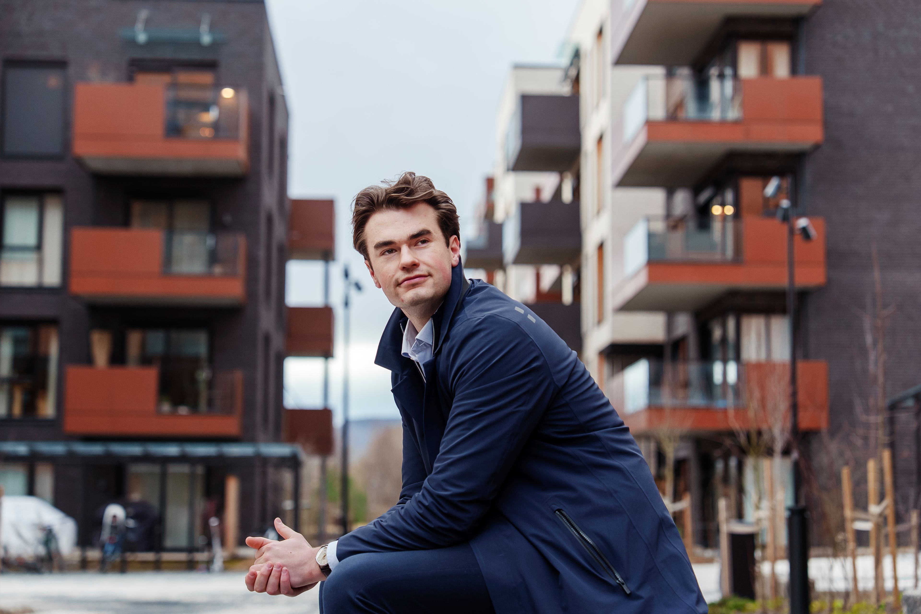 Oskar sitter på en benk utenfor nybygg i Storøykilen på Fornebu.