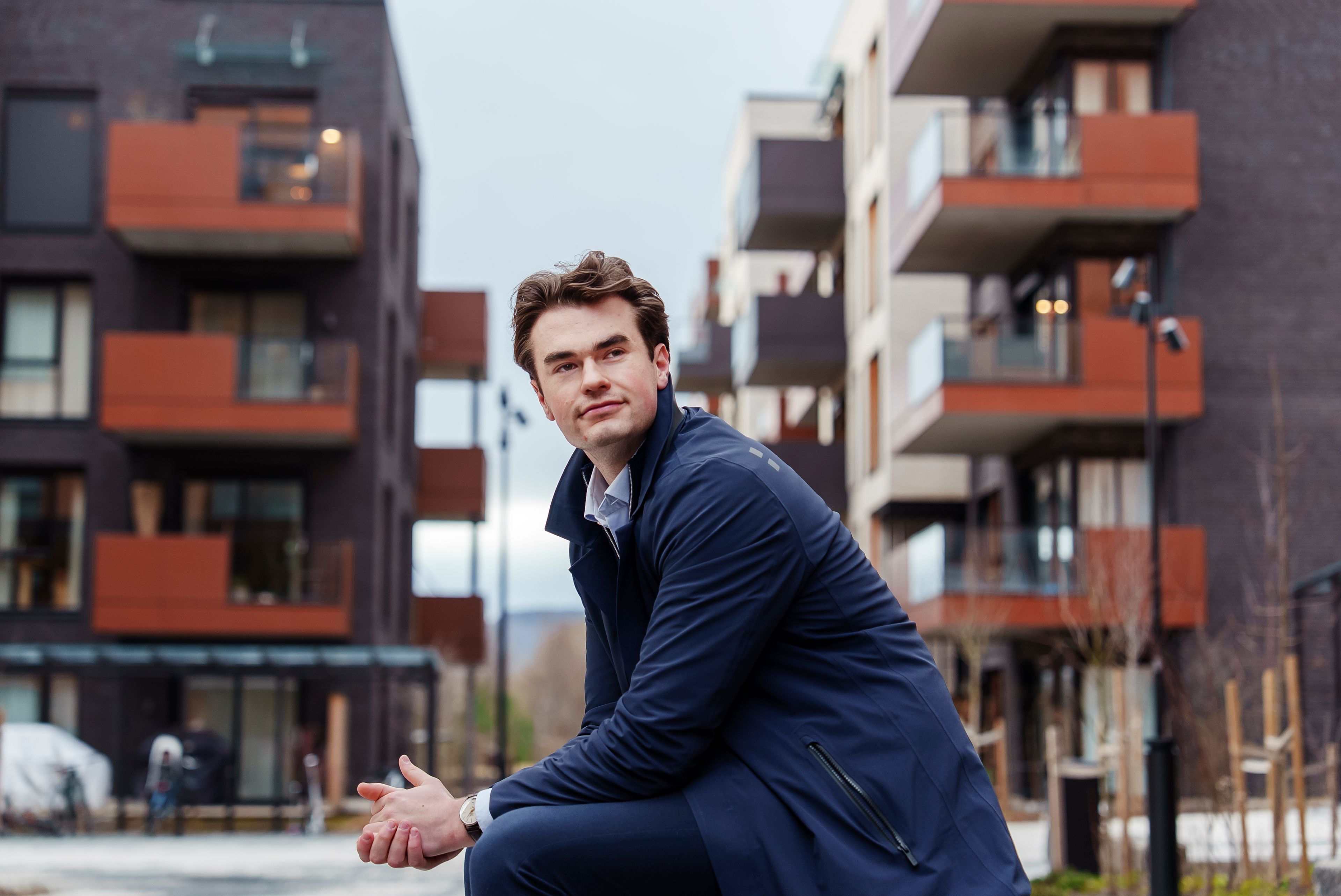Oskar sitter på en benk utenfor nybygg i Storøykilen på Fornebu.