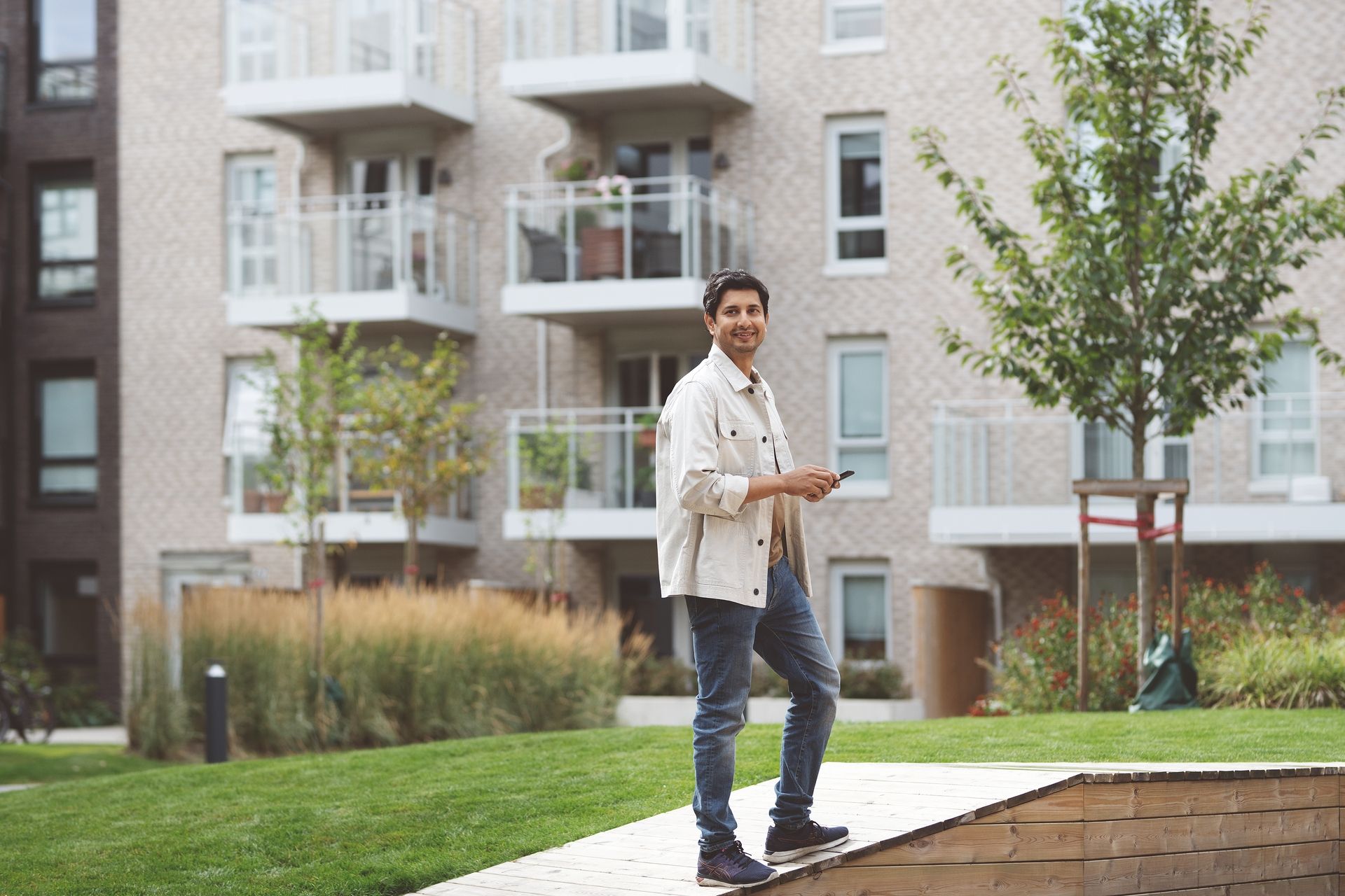 En mann venter i gårdsrommet utenfor leiligheten sin.