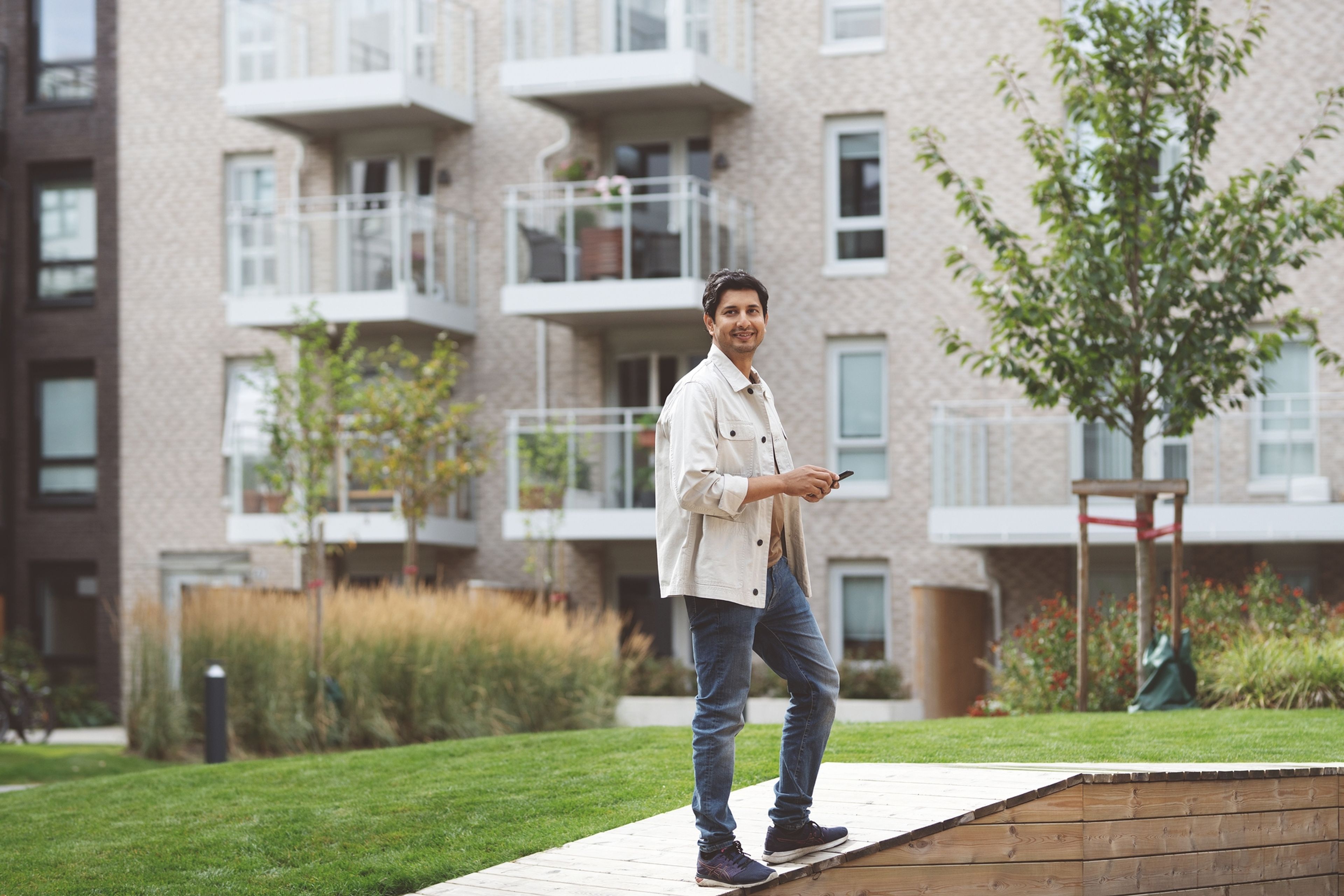 En mann venter i gårdsrommet utenfor leiligheten sin.