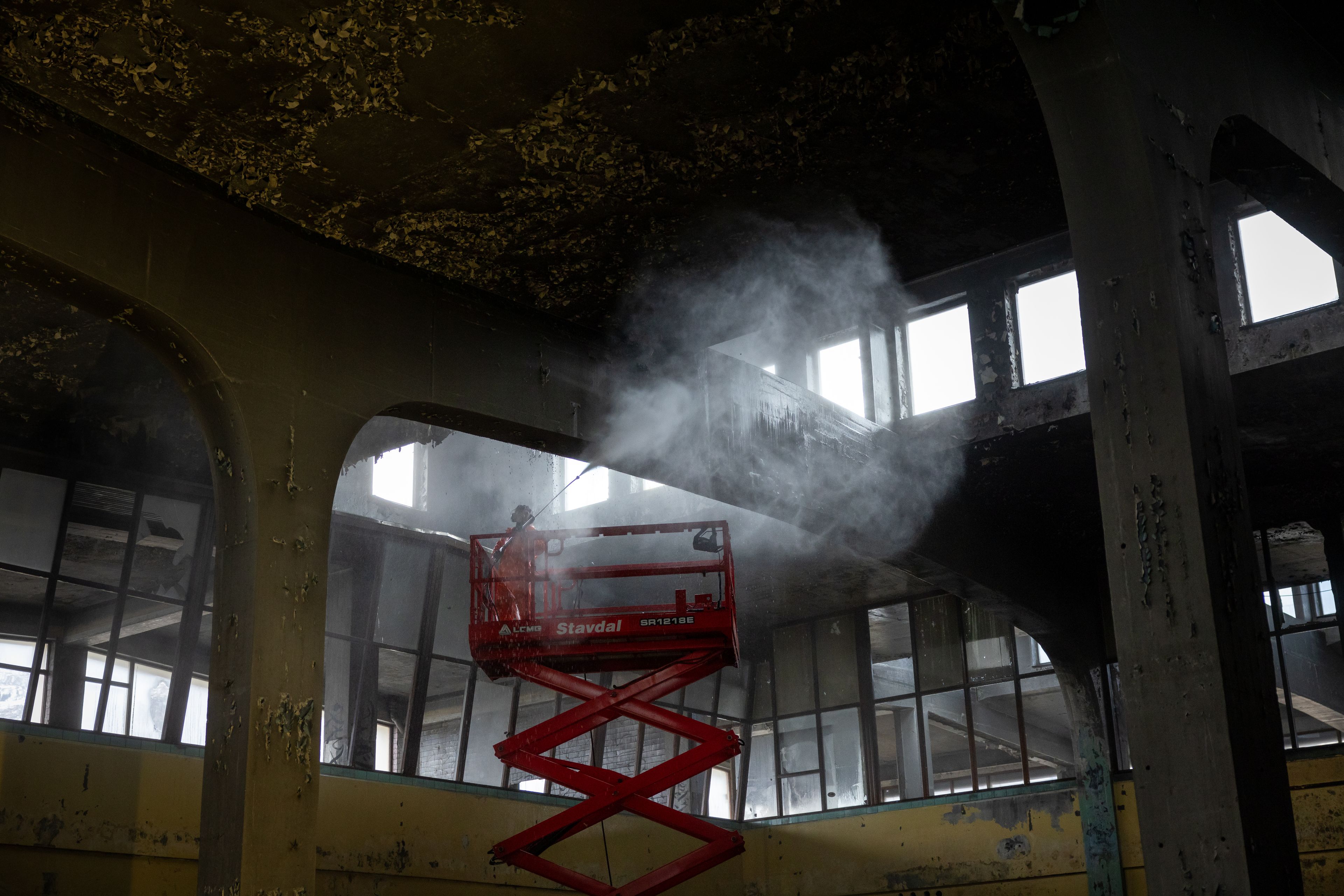 Saneringsarbeider står på en kran og spyler taket inne på Tapperiet.