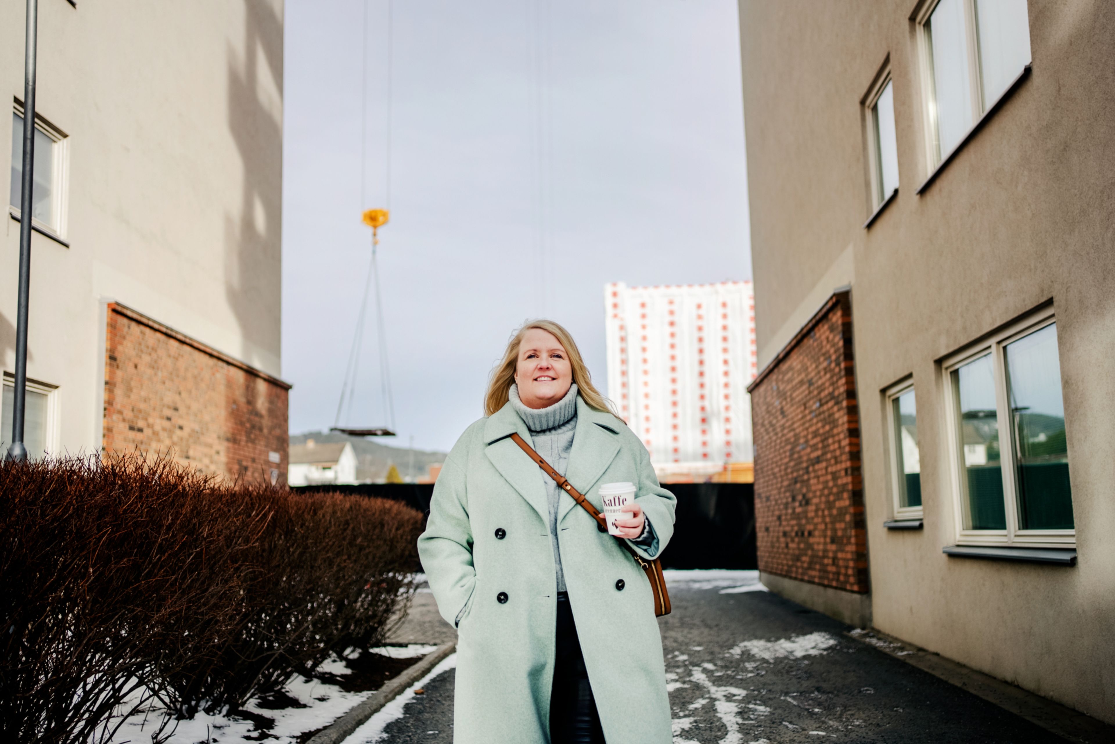 Portrett av Josefin gående mellom bygninger på Løren, med heisekran i bakgrunnen.