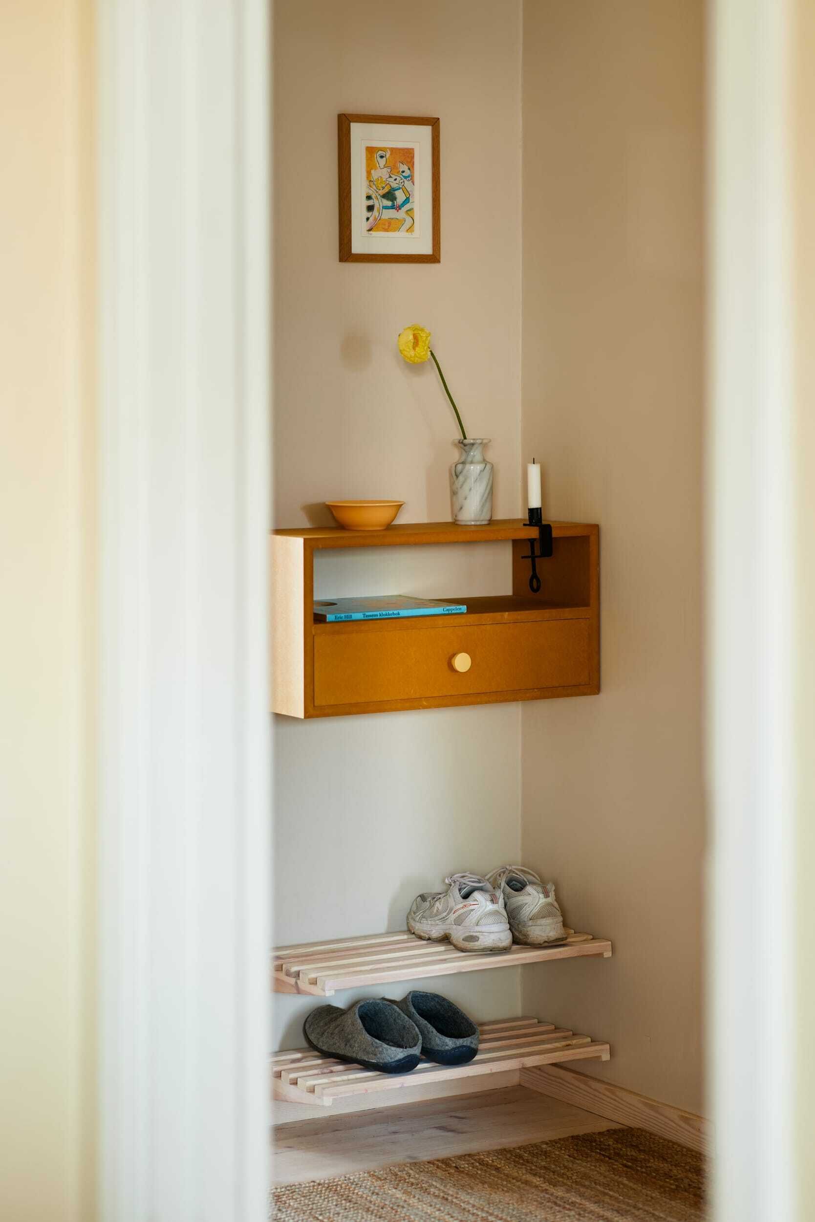 Vegghengt gul hylle og skohyller i lyst tre i gangen.